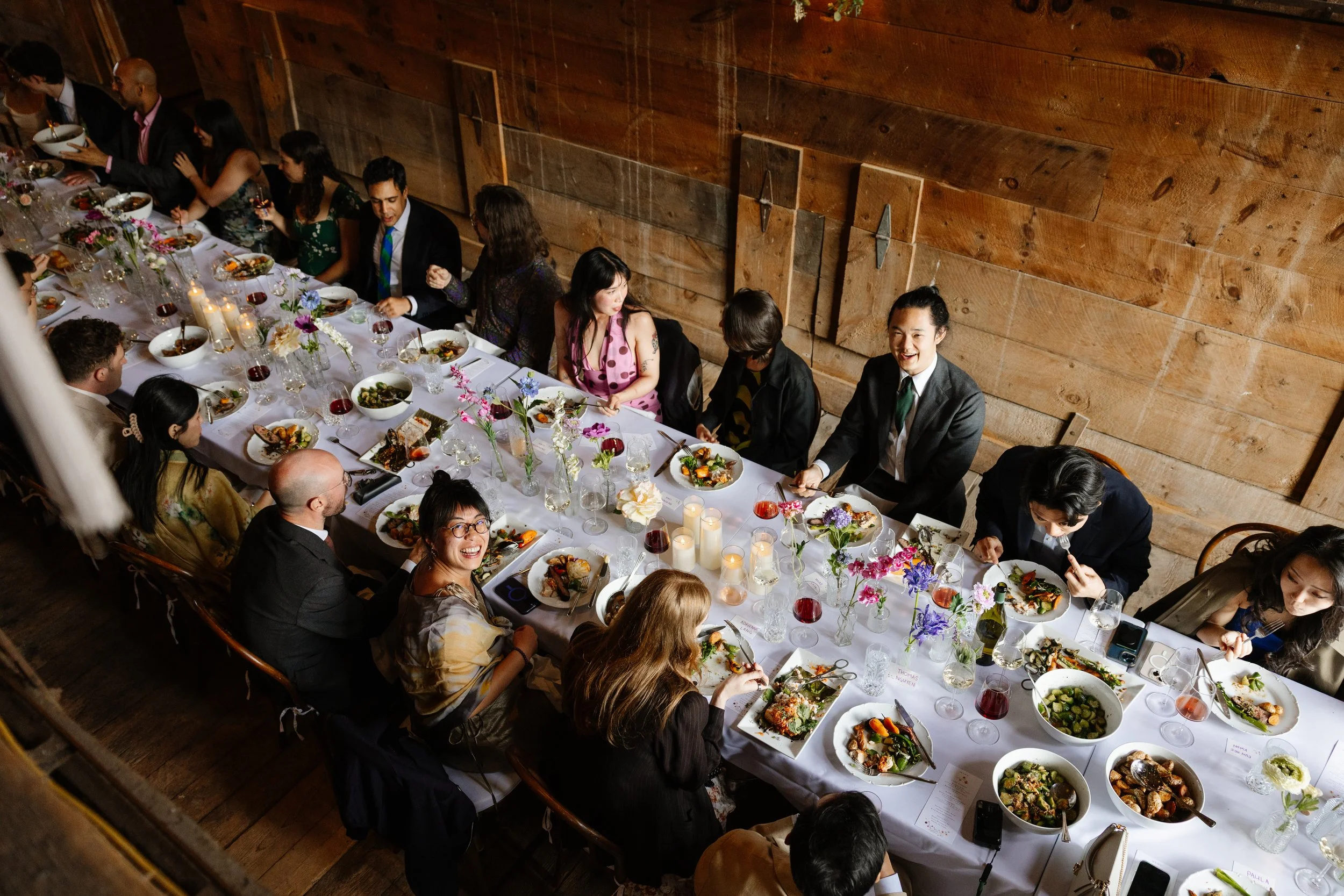 Guests sit down for a family style dinner during a small backyard wedding in Norway, Maine. Photography by Sienna Renee Photography.