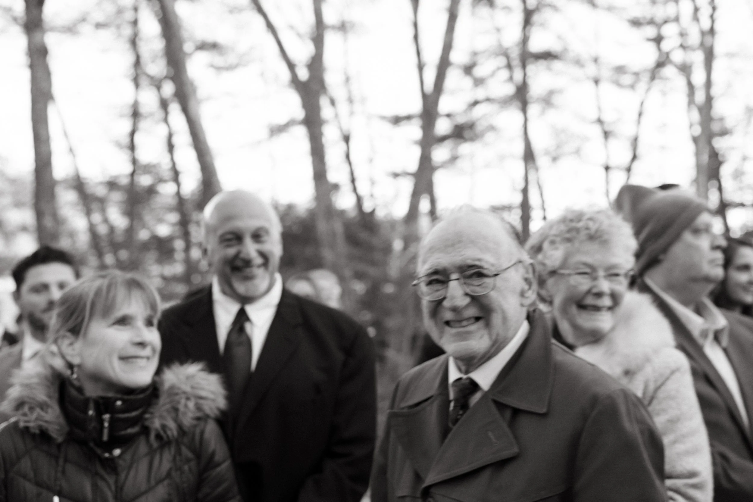 Guests smile during an intimate winter wedding ceremony at The Barn at Hatch Point in Bowdoinham, Maine. Photography by Sienna Renee Photography.