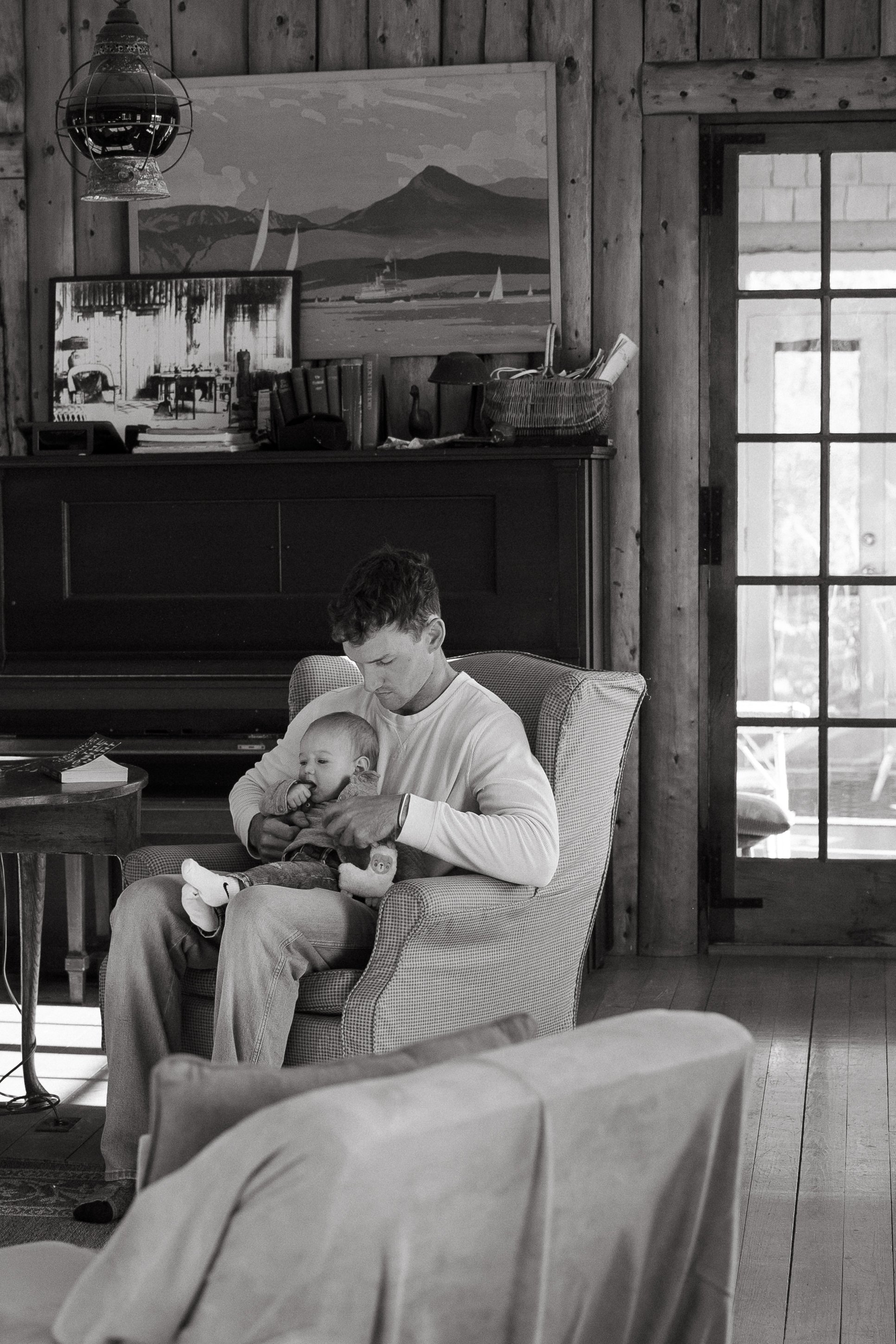 A dad sits with his baby during a visit to a rental in Maine. Photography by Sienna Renee Photography.