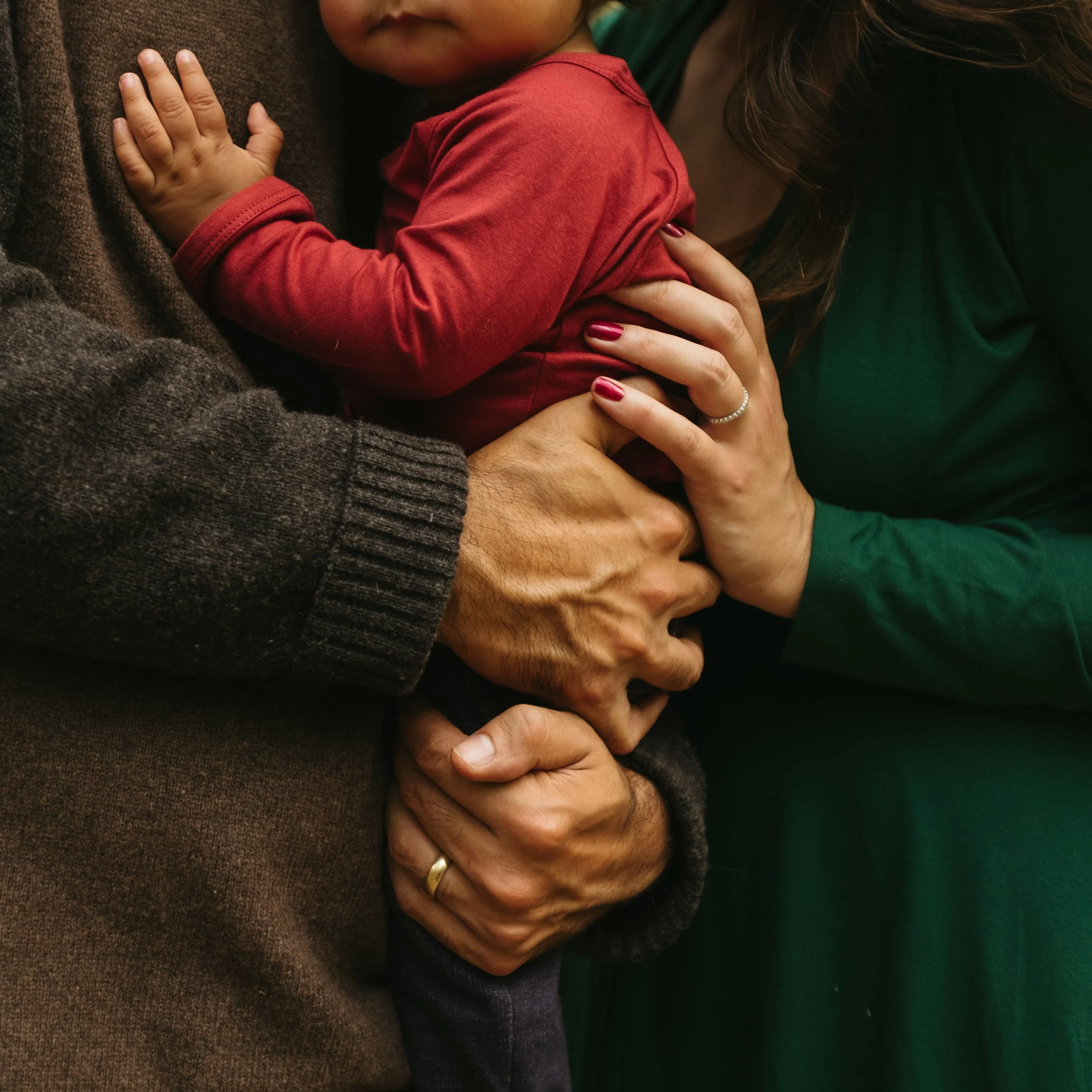 Details of a family's hands as they hold their baby during a photo session in the woods of Maine. Photography by Sienna Renee Photography.