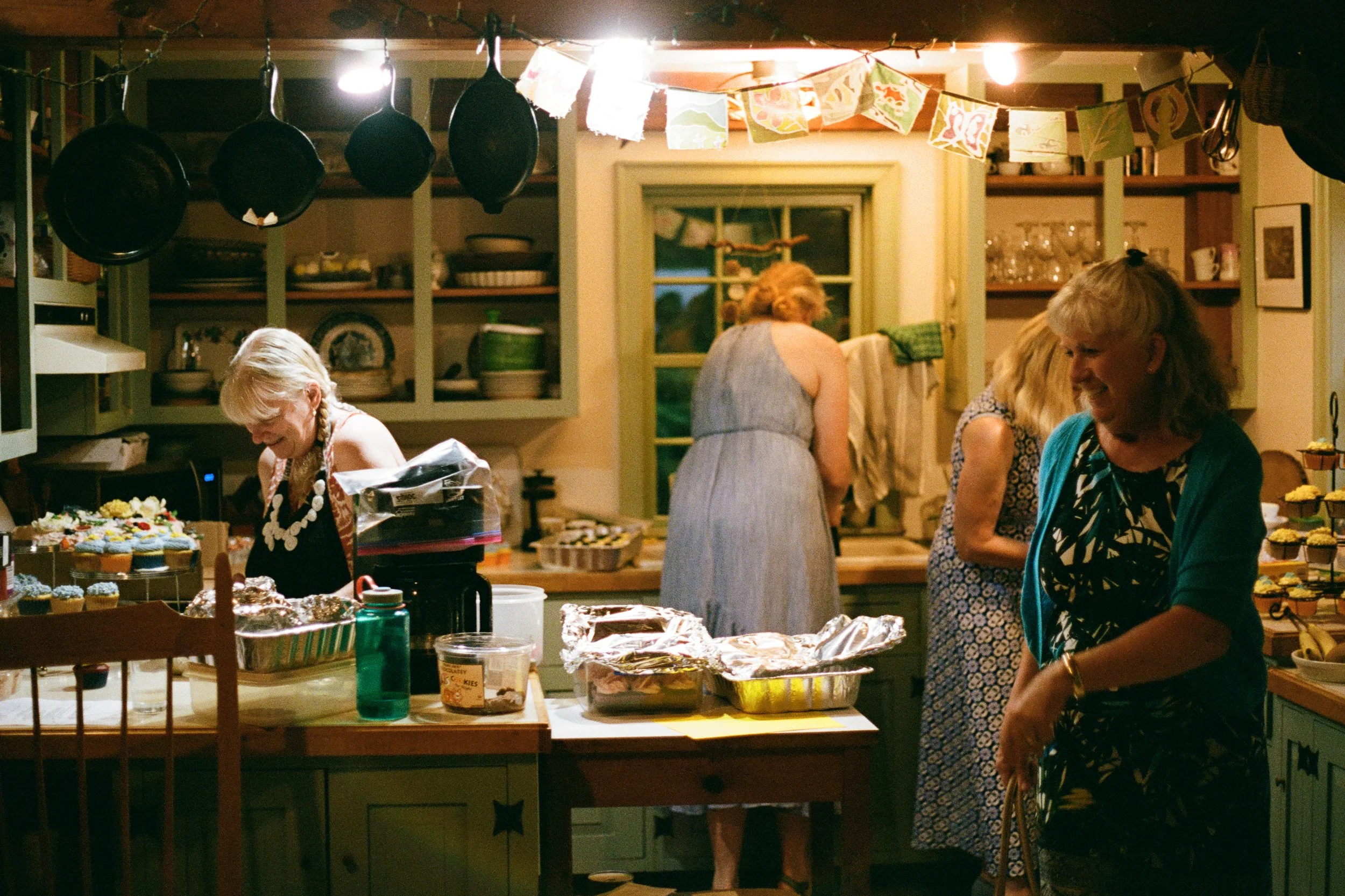 Family helps gather food during a rainy backyard wedding in Maine. Photography by Sienna Renee Photography.