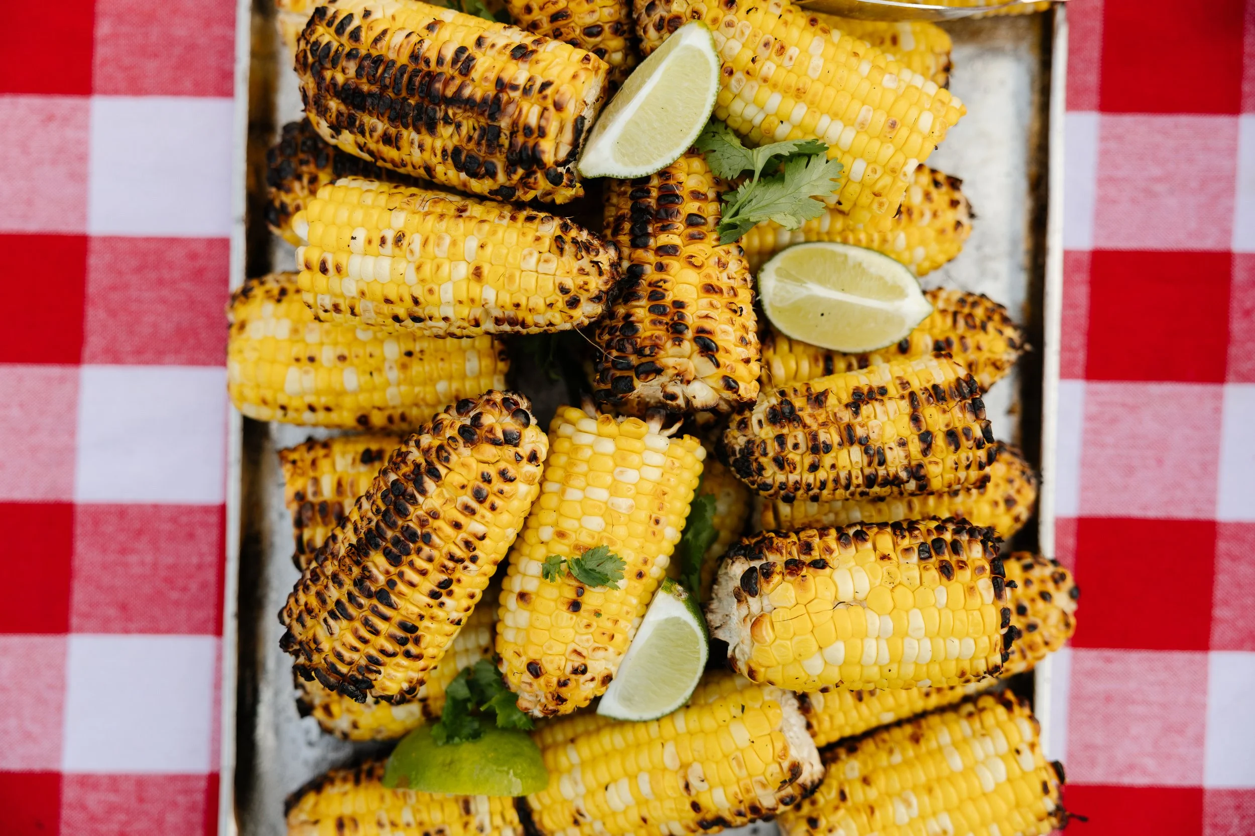 Corn during a lobster bake for a welcome dinner during an intimate wedding weekend at Aragosta at Goose Cove in Deer Isle, Maine. Photography by Sienna Renee Photography.