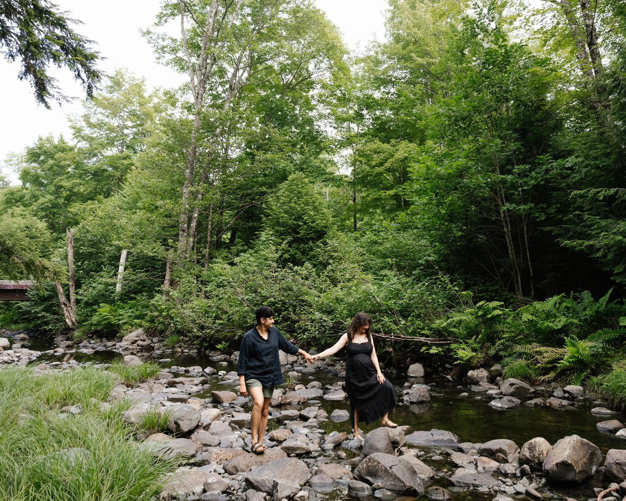 A coupls holds hands and walks together during their babymoon in Moosehead Lake, Maine. Photography by Sienna Renee Photography.