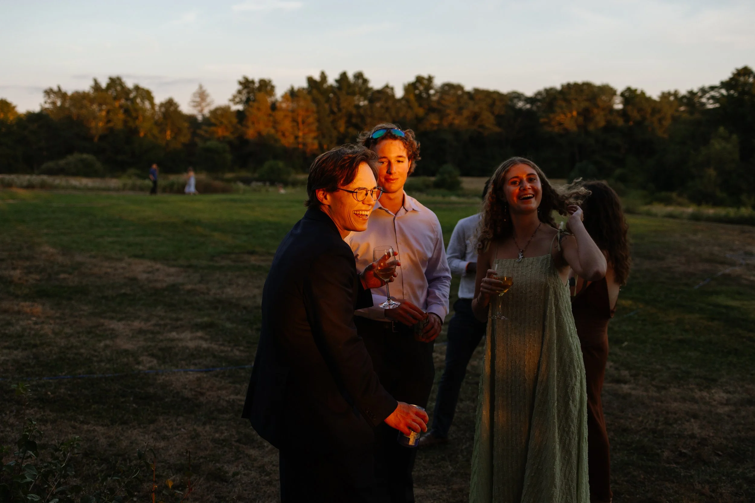 Friends laugh together during a wedding at Scotland Fields in York, Maine. Photography by Sienna Renee Photography.