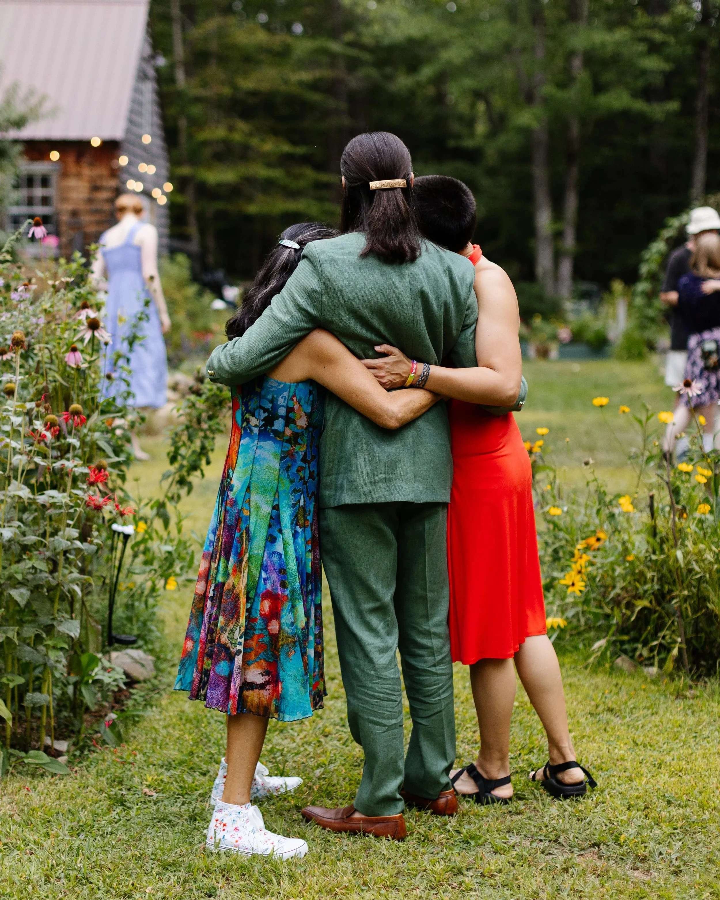 A groom and his mom and sister hug during his backyard wedding in North Berwick, Maine. Photography by Sienna Renee Photography.