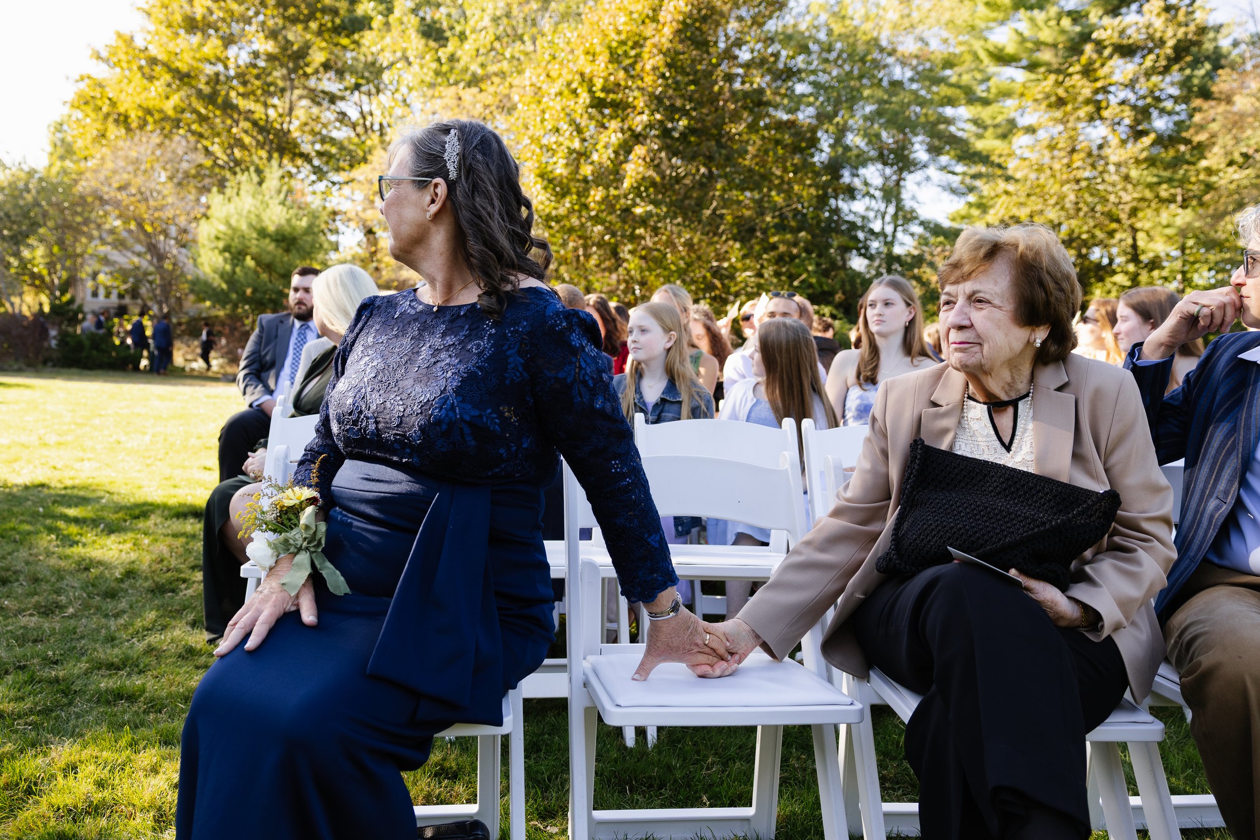 Family holds hands during a ceremony in York, Maine. Photography by Sienna Renee Photography.