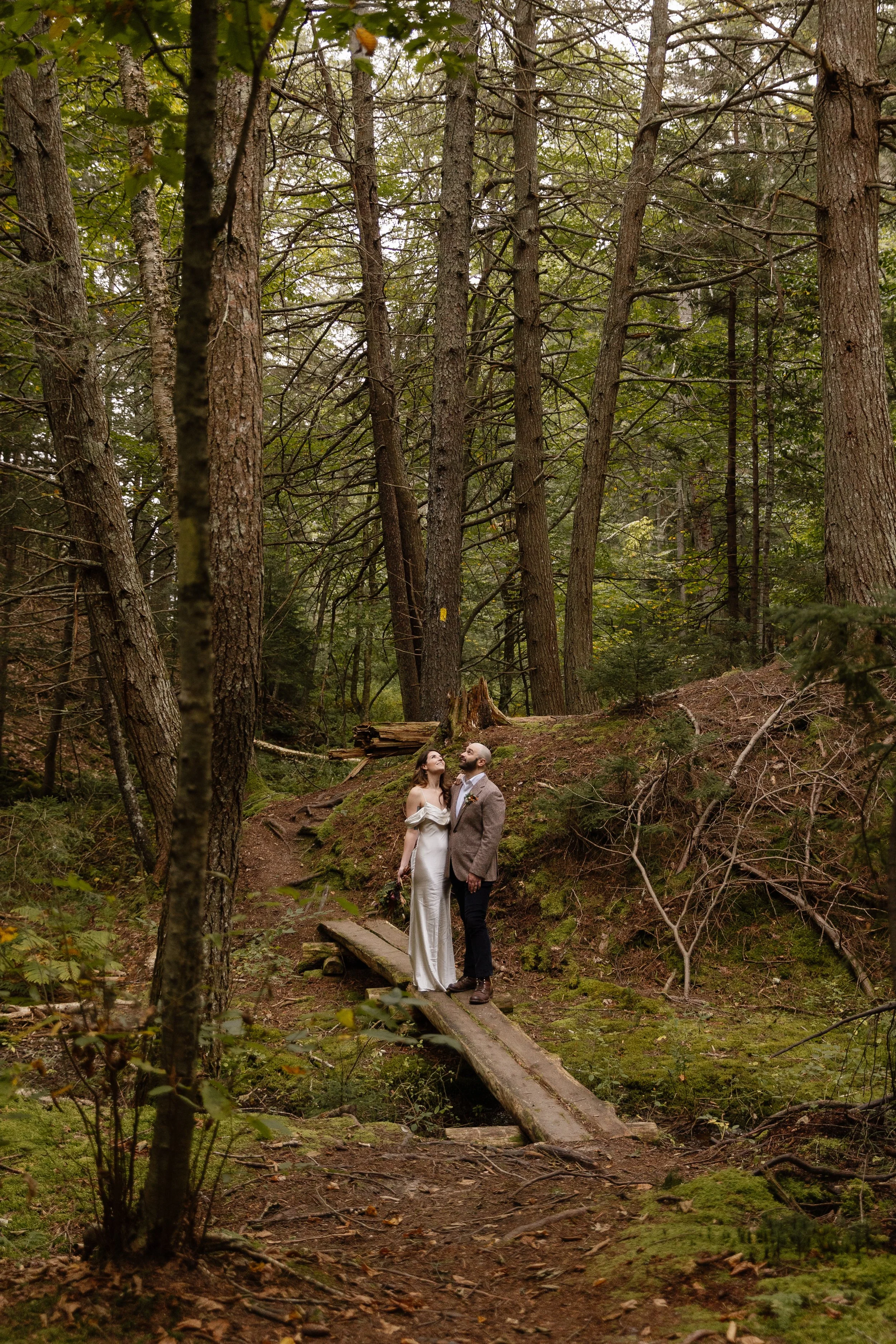 A couple stands in the woods during their intimate wedding day in Midcoast Maine. Photography by Sienna Renee Photography.