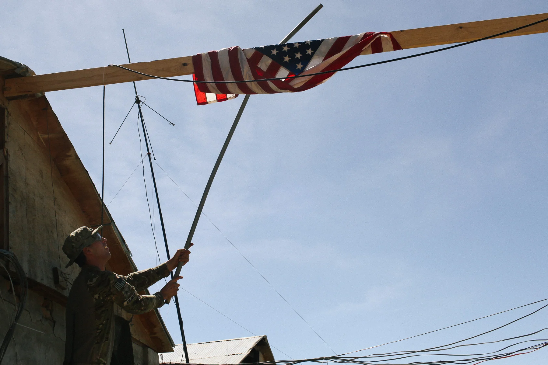 A US soldier tries to untangle a flag after a stormy night.