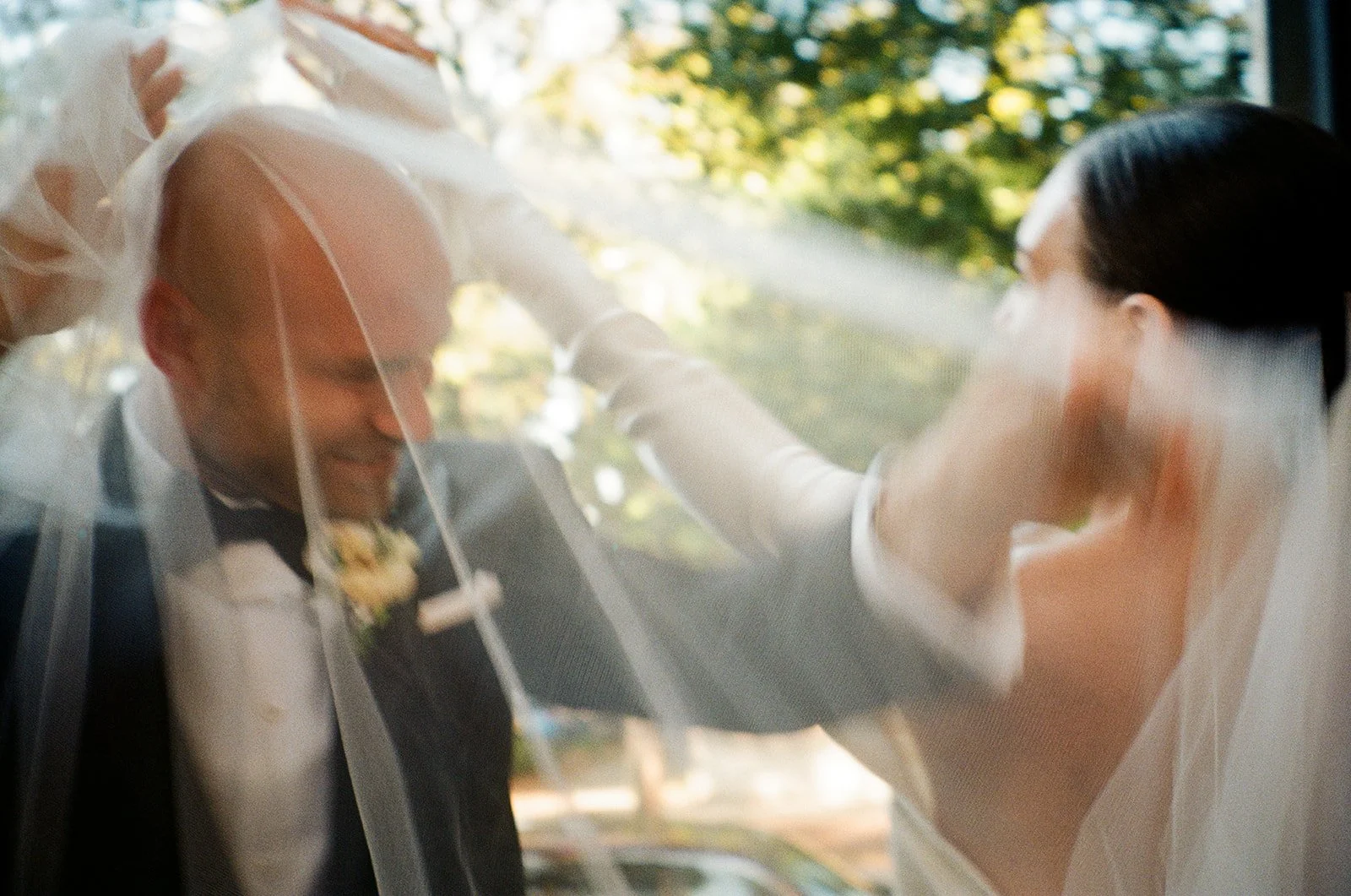 A bride and groom play with bride's veil during portraits at their romantic garden wedding at Harper Fowlkes House in Savannah, Georgia.