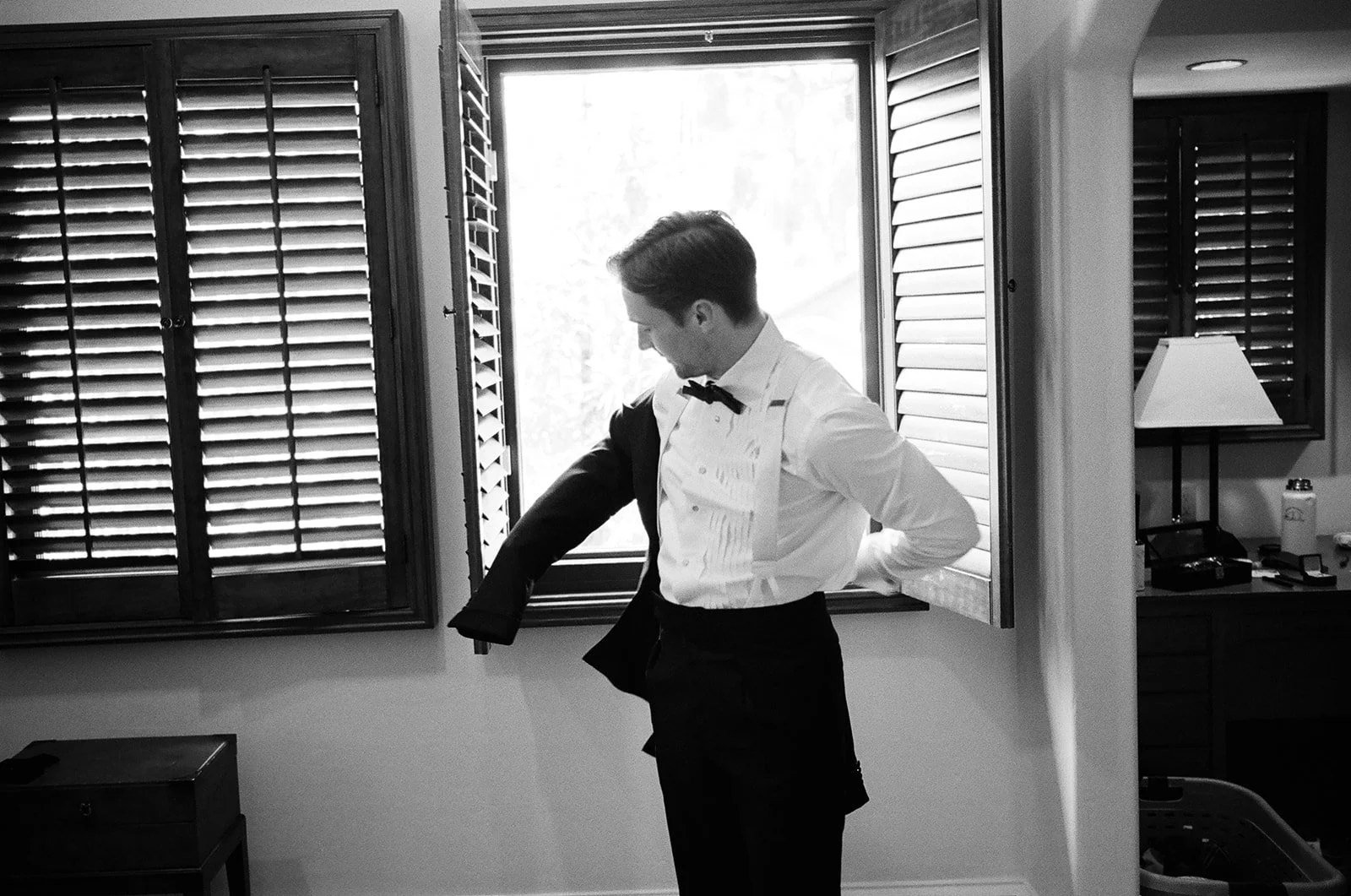 A groom puts on his jacket as he gets ready at the Langham hotel in Los Angeles for his family home outdoor wedding in Pasadena, California.