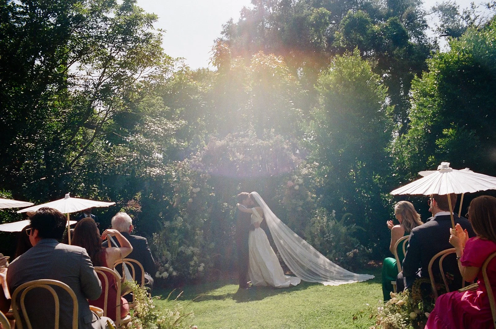 Bride and groom share their first kiss at the end of their garden ceremony just outside of Los Angeles, California.