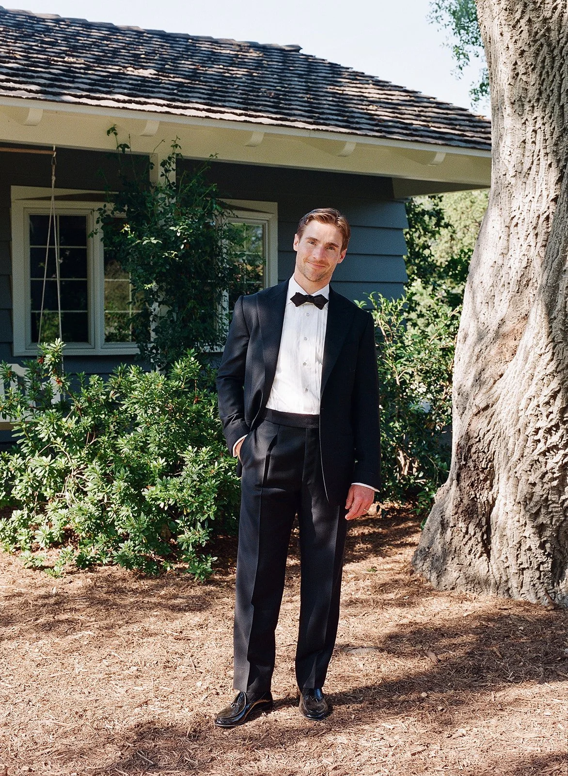 Chef groom poses for wedding portrait in front of family home in Pasadena, California outside of Los Angeles.