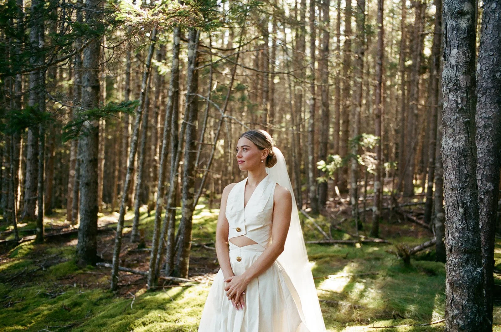 Bride poses for a film portrait in the woods at Aragosta wedding in Maine.
