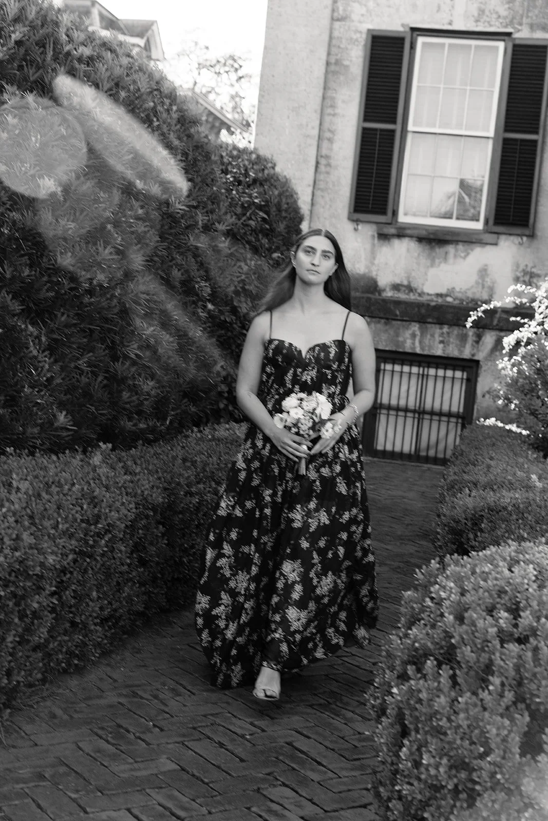 Bridesmaid walks down the aisle during outdoor garden ceremony at Harper Fowlkes House in Savannah, Geogria.