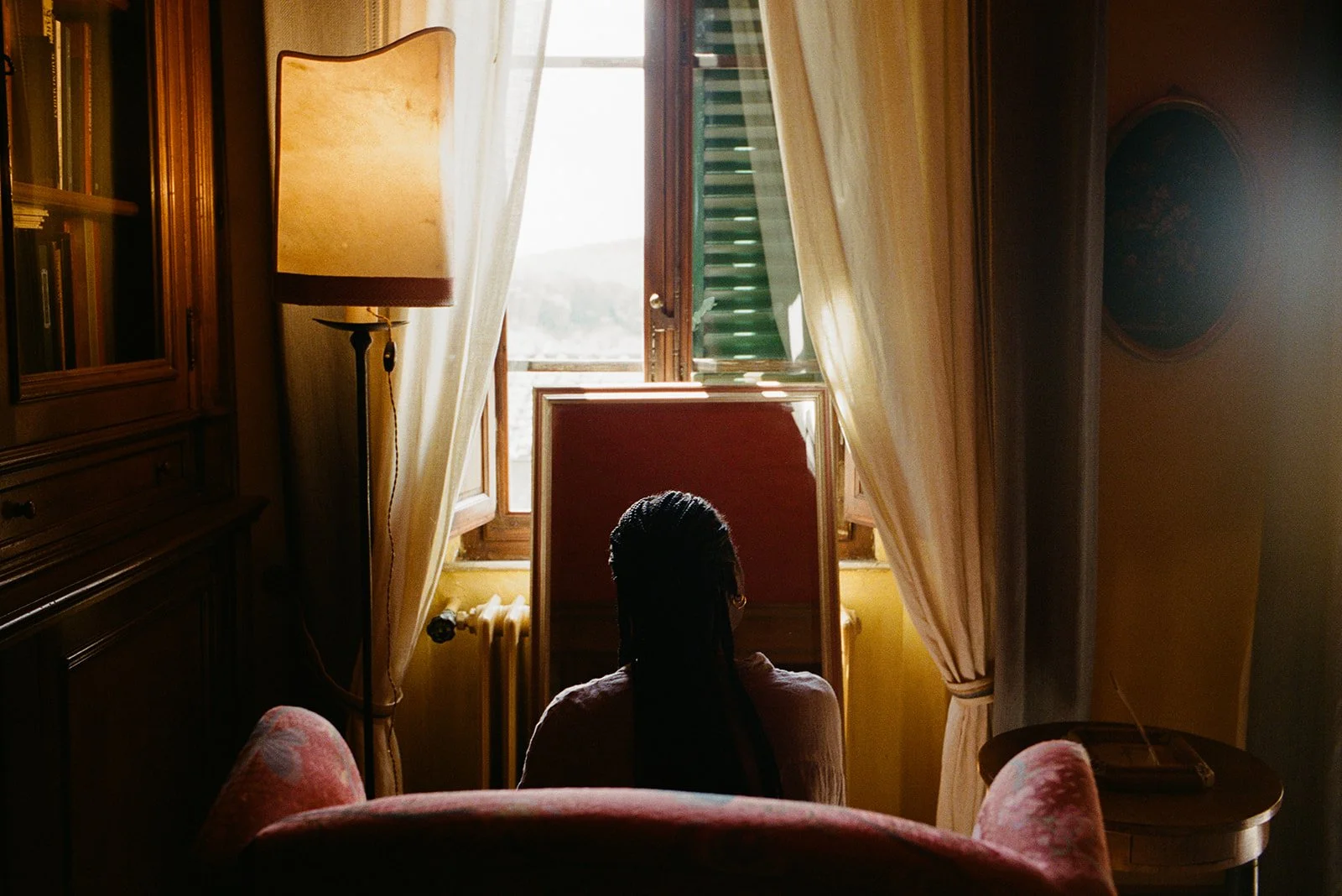 A bridesmaid gets ready in a romantic, warmly lit room of a villa in Tuscany, Italy.