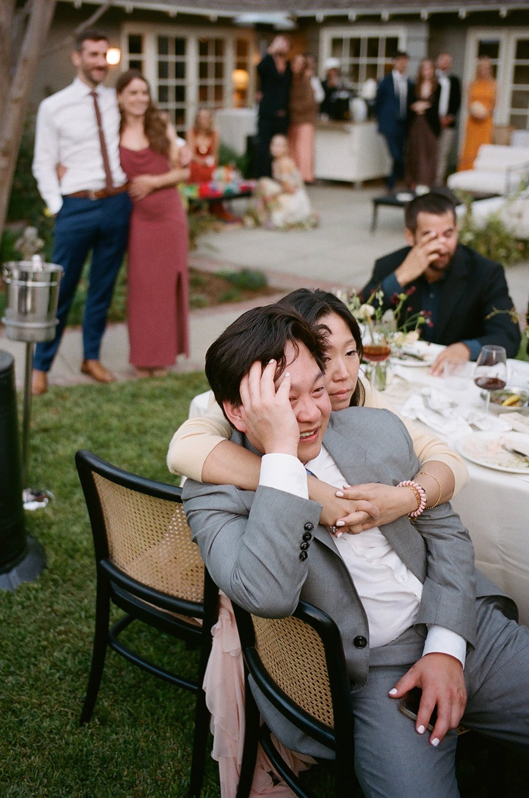 Wedding guests embrace in tears as they listen to speeches at garden wedding in Pasadena, California wedding, outside of LA.
