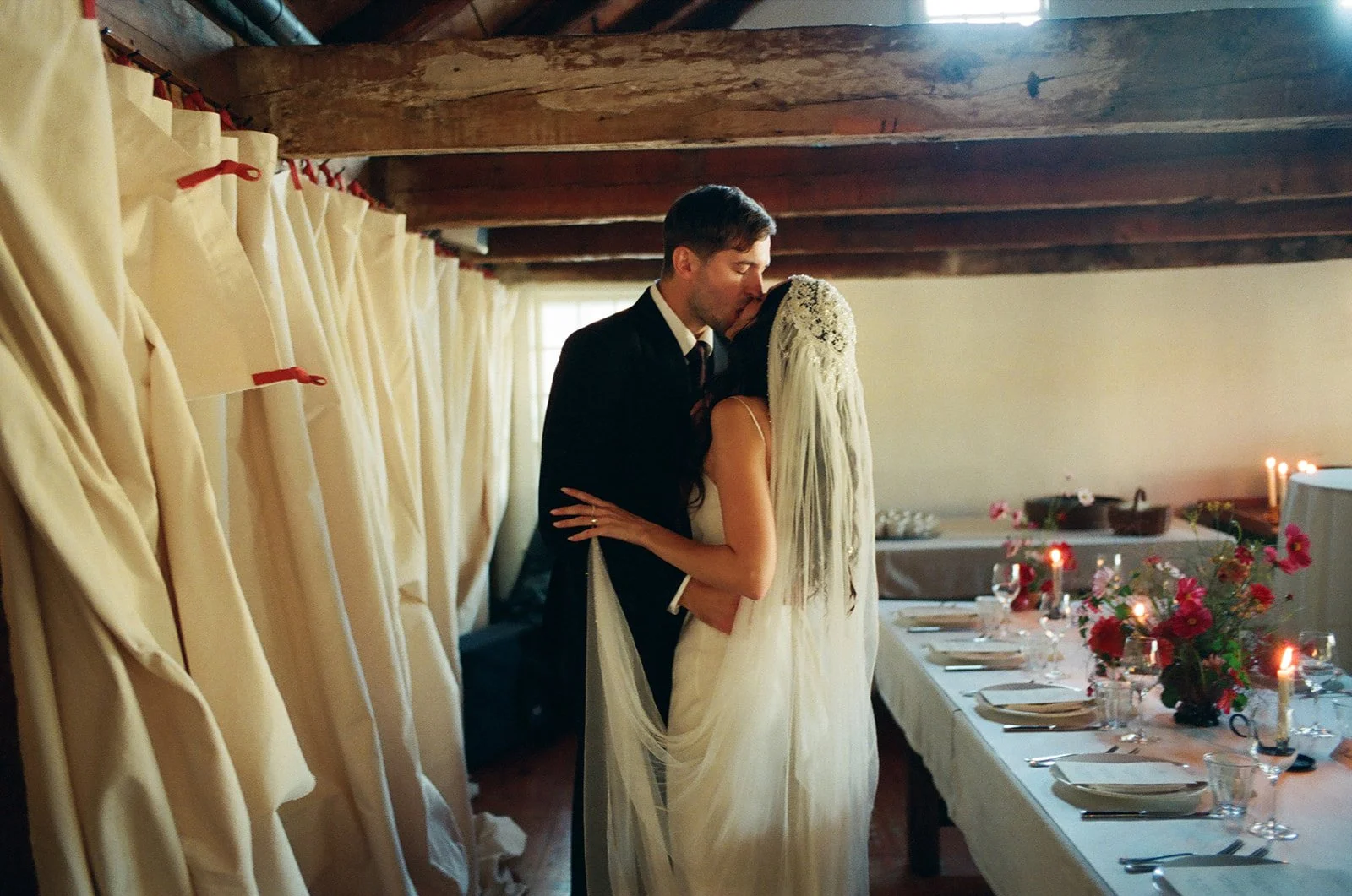 A bride wearing a custom Paula Nadal veil and Tab vintage silk wedding gown kisses her groom just after their ceremony at Stissing House in Upstate New York.