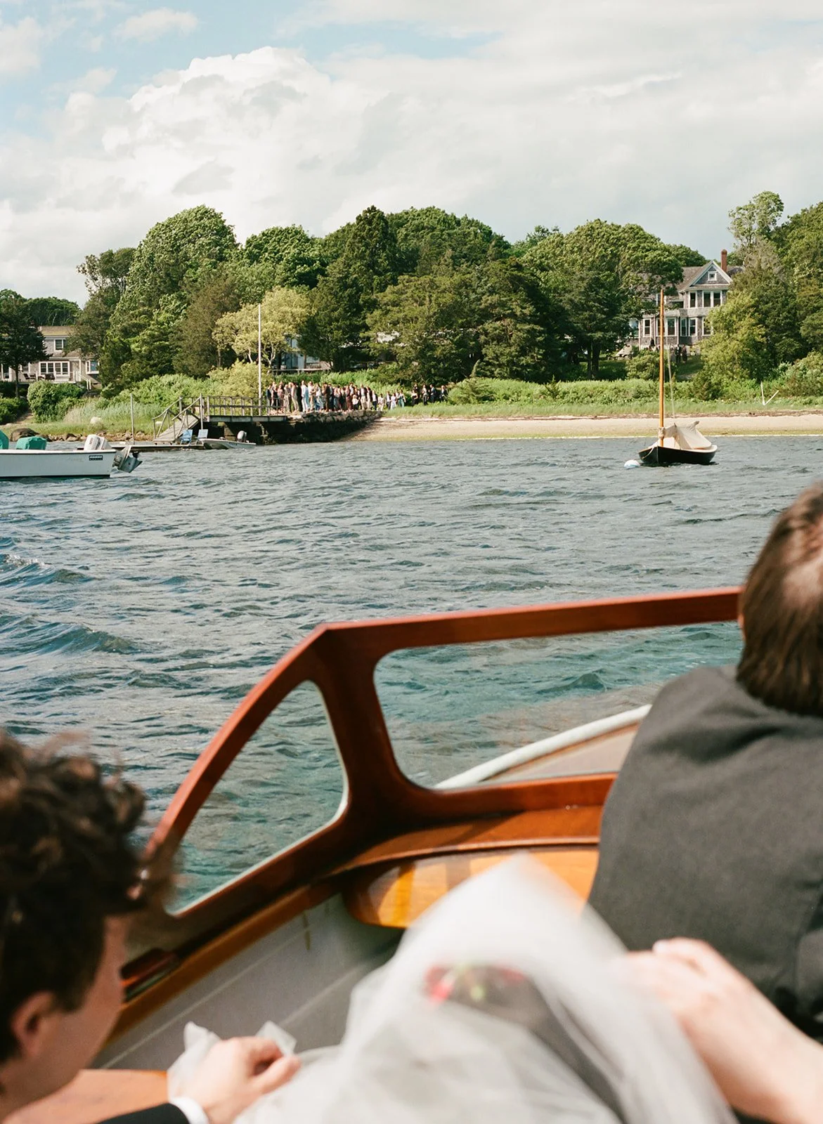 Couple rides boat to shore along the coast of Cape Cod during their wedding in Massachusetts.