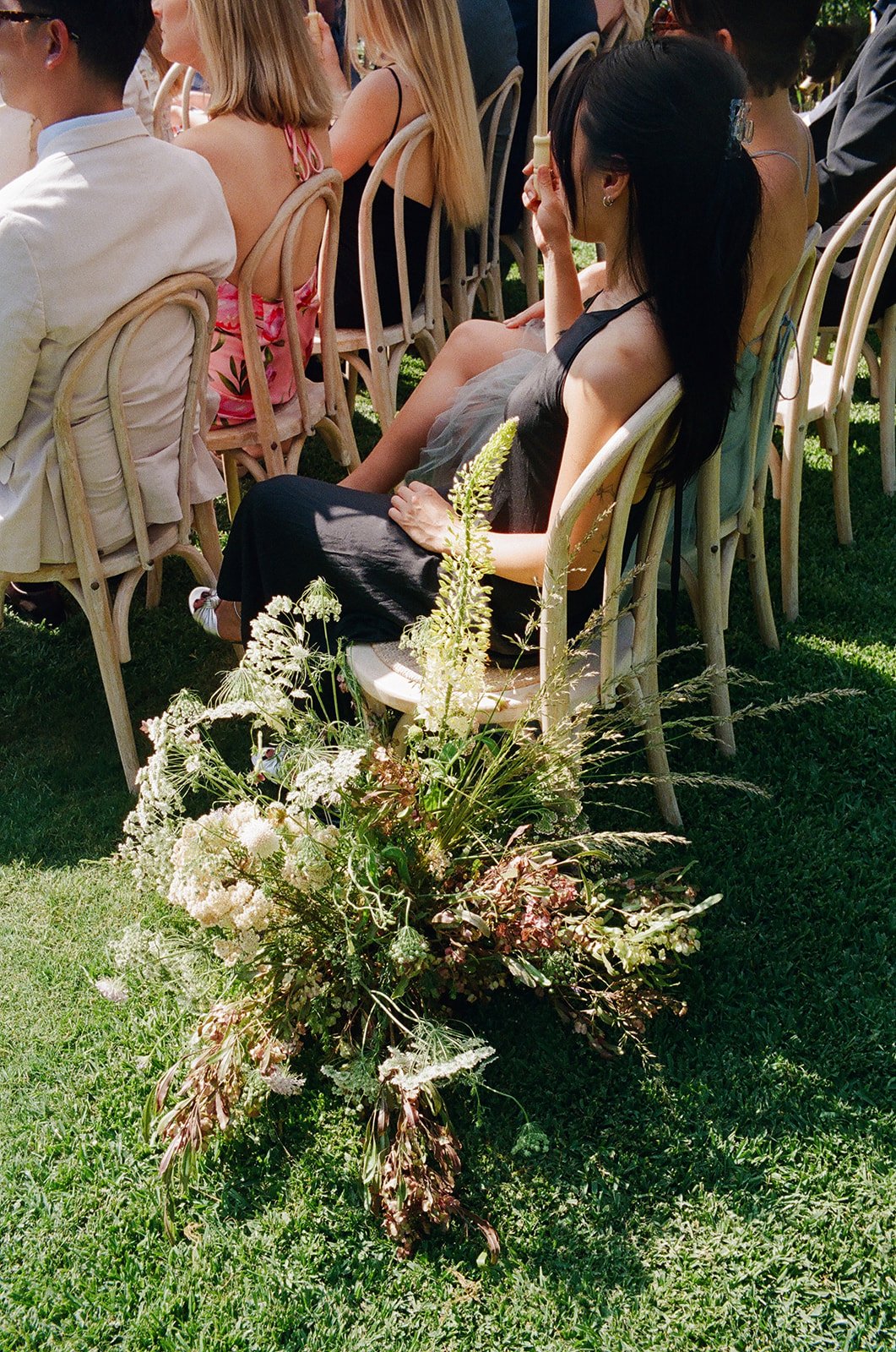 Guest watches during sunny, outdoor wedding ceremony in Los Angeles, California