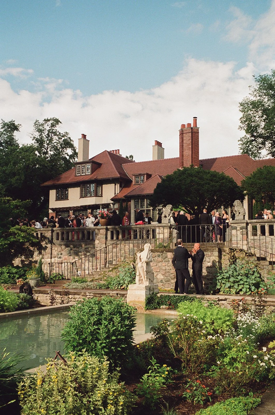 Wedding guests enjoy an outdoor cocktail hour at Cranbrook House and Gardens near Detroit, Michigan.