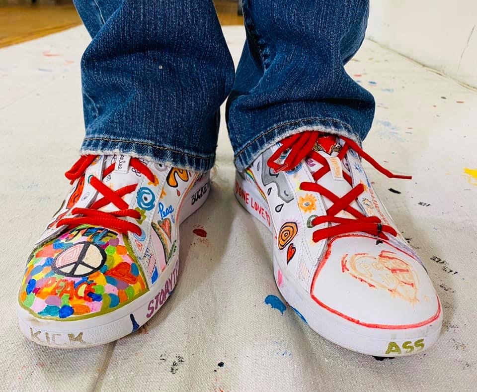 PeaceLove shoes. One says "Kick" and one says "Ass" on the tips of the shoes