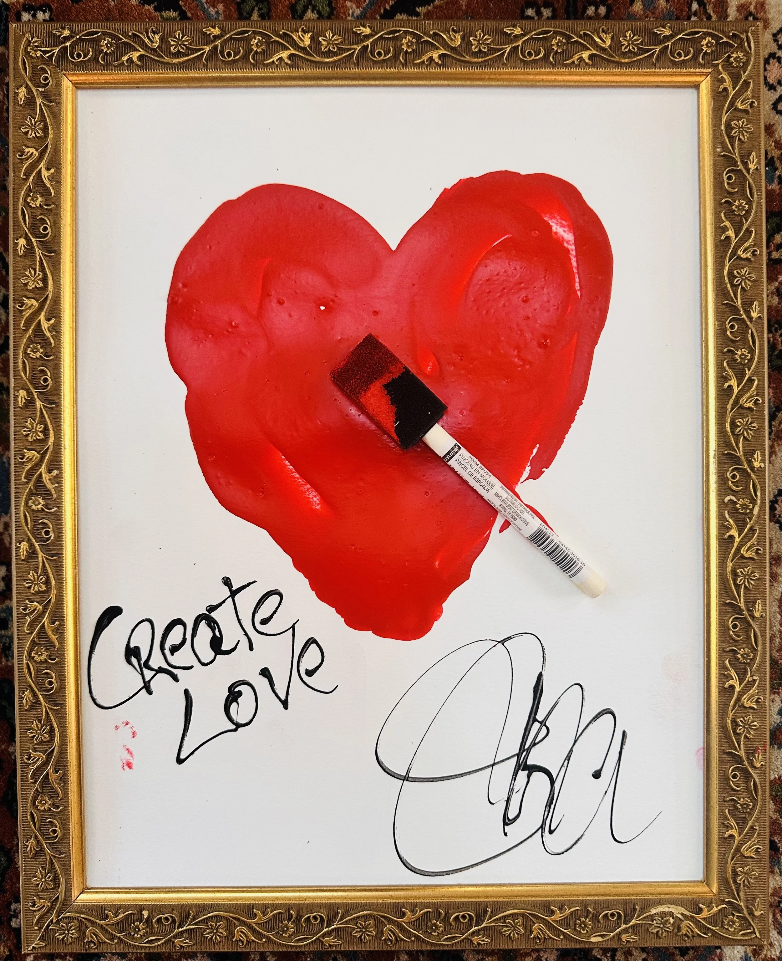 Framed painting of red heart that says, "Create Love"