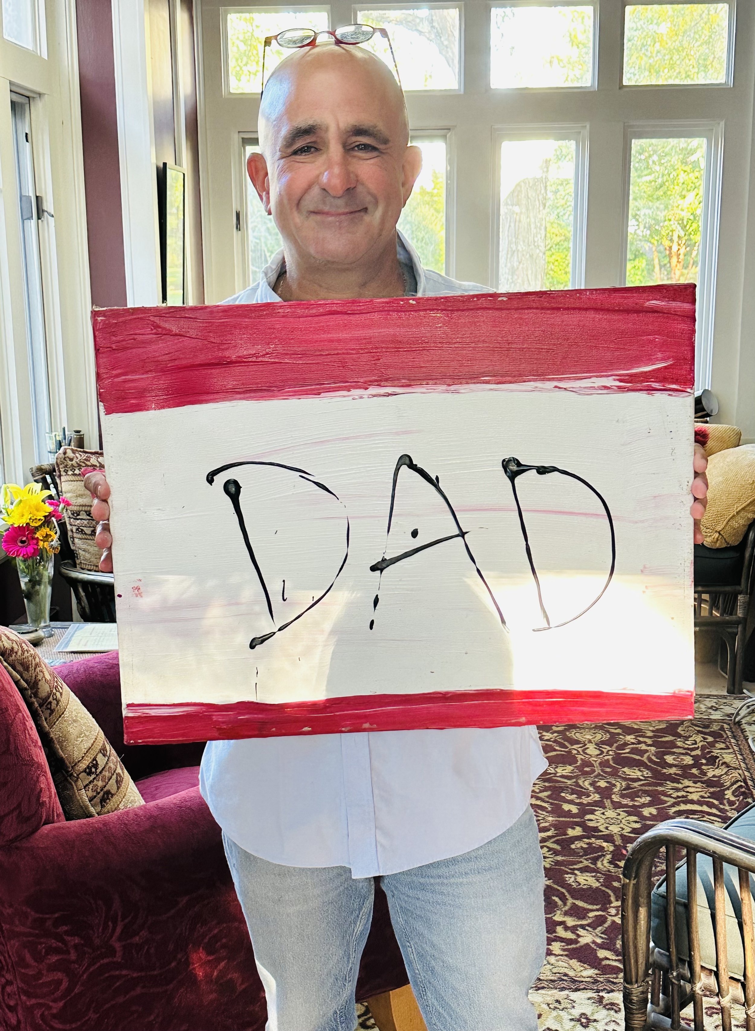 Jeff holding up a painting that says, "DAD"