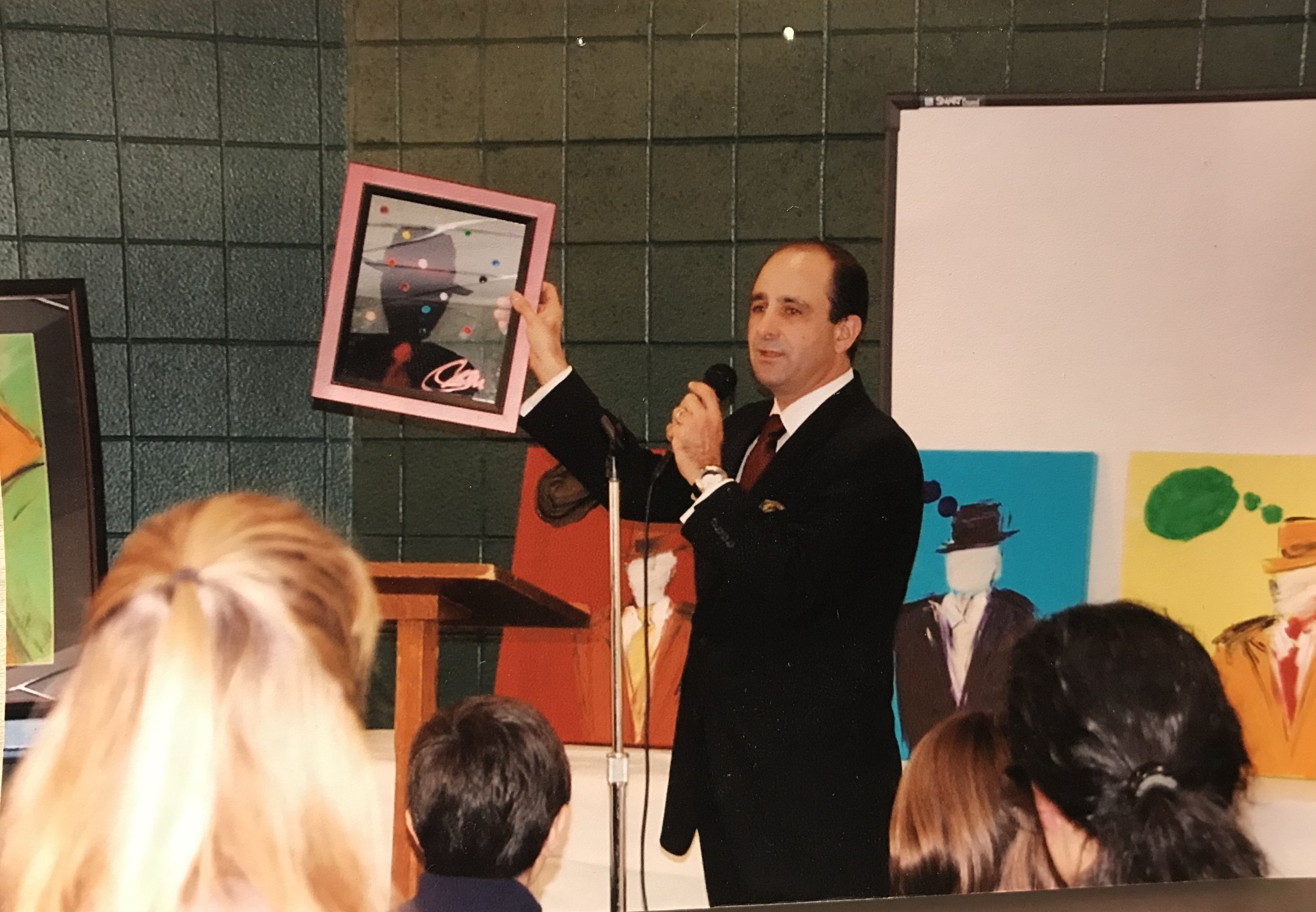 Jeff holding up a painting while speaking.