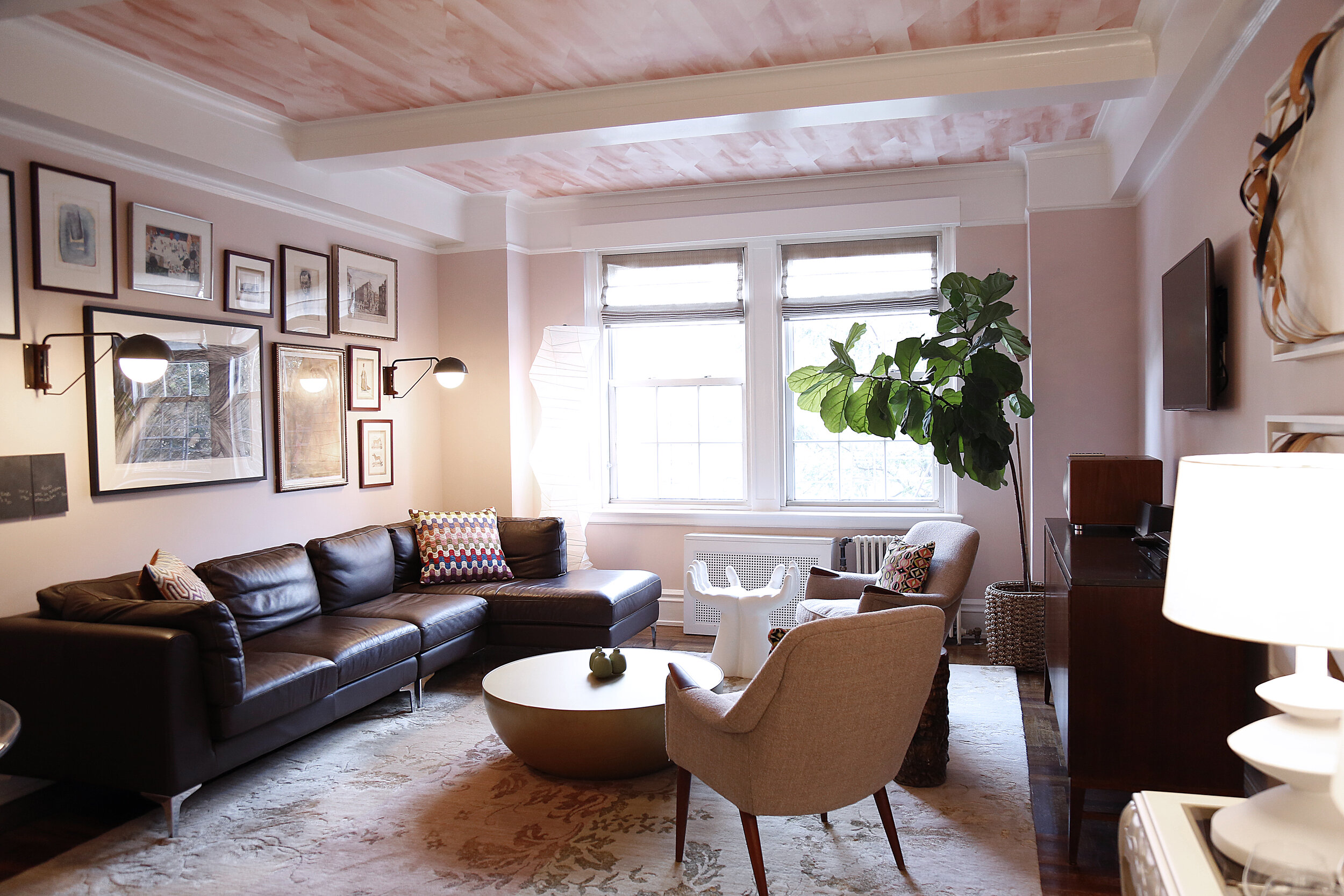 Modern living room with mauve walls and wallpaper ceiling, brown leather sectional and vintage furniture