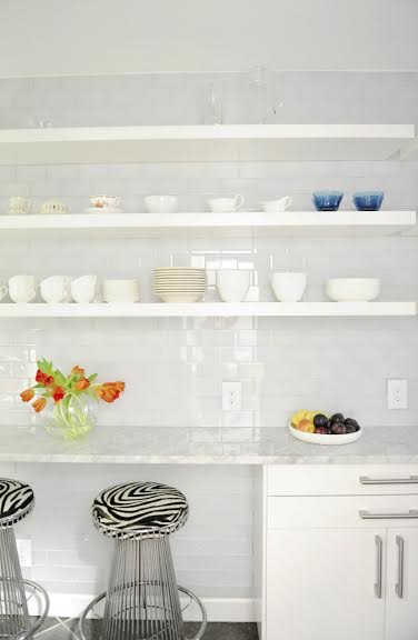 White kitchen with custom floating shelves and glass subway tiles 