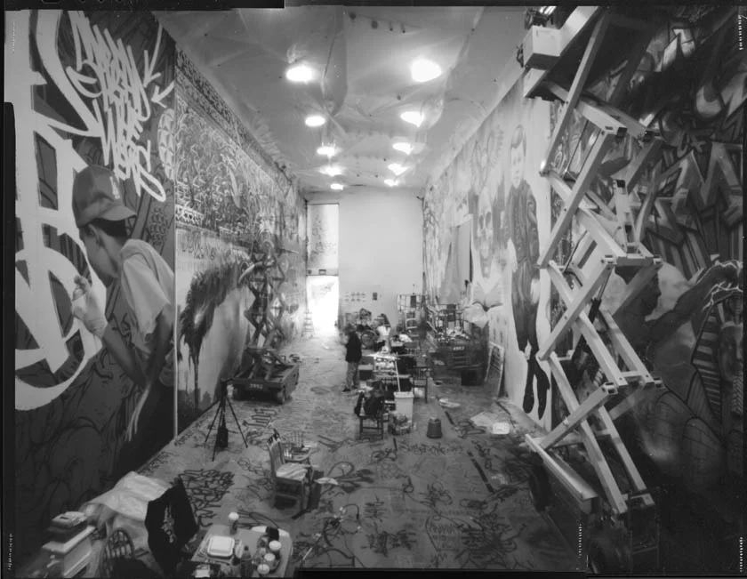 Stitched together, 3-panel, pinhole shot of the construction of the exhibition