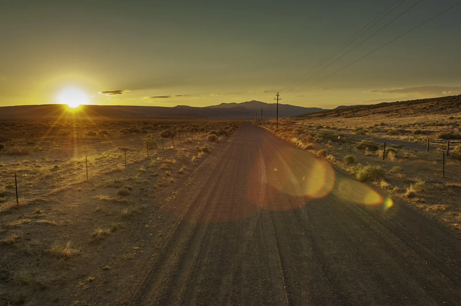 Desolate road with power lines at sunrise