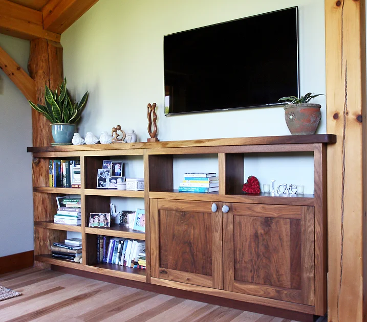 The open shelves of this walnut shelf system were hand scribed to fit the curve of the peeled oak post.