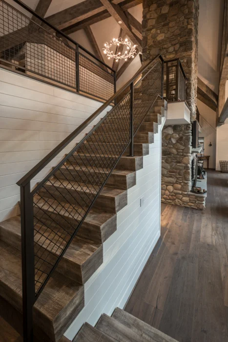 Custom-finished timber stairs in a Finger Lakes cottage home lead the way to an upstairs loft space. © Scott Hemenway