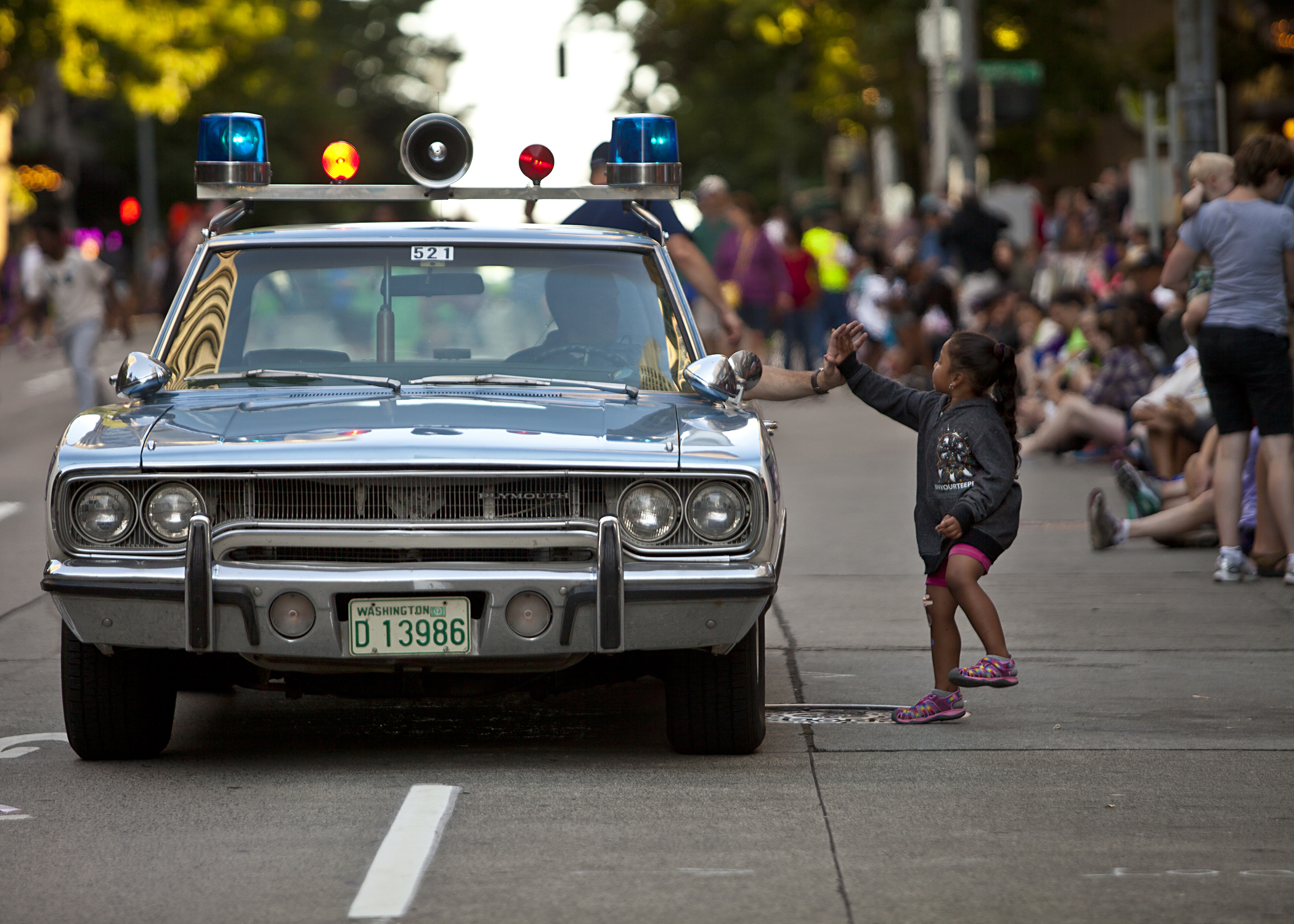  One little girl offers a Seattle Police Officer a high-five during the 2014 Torchlight Parade.&nbsp; 