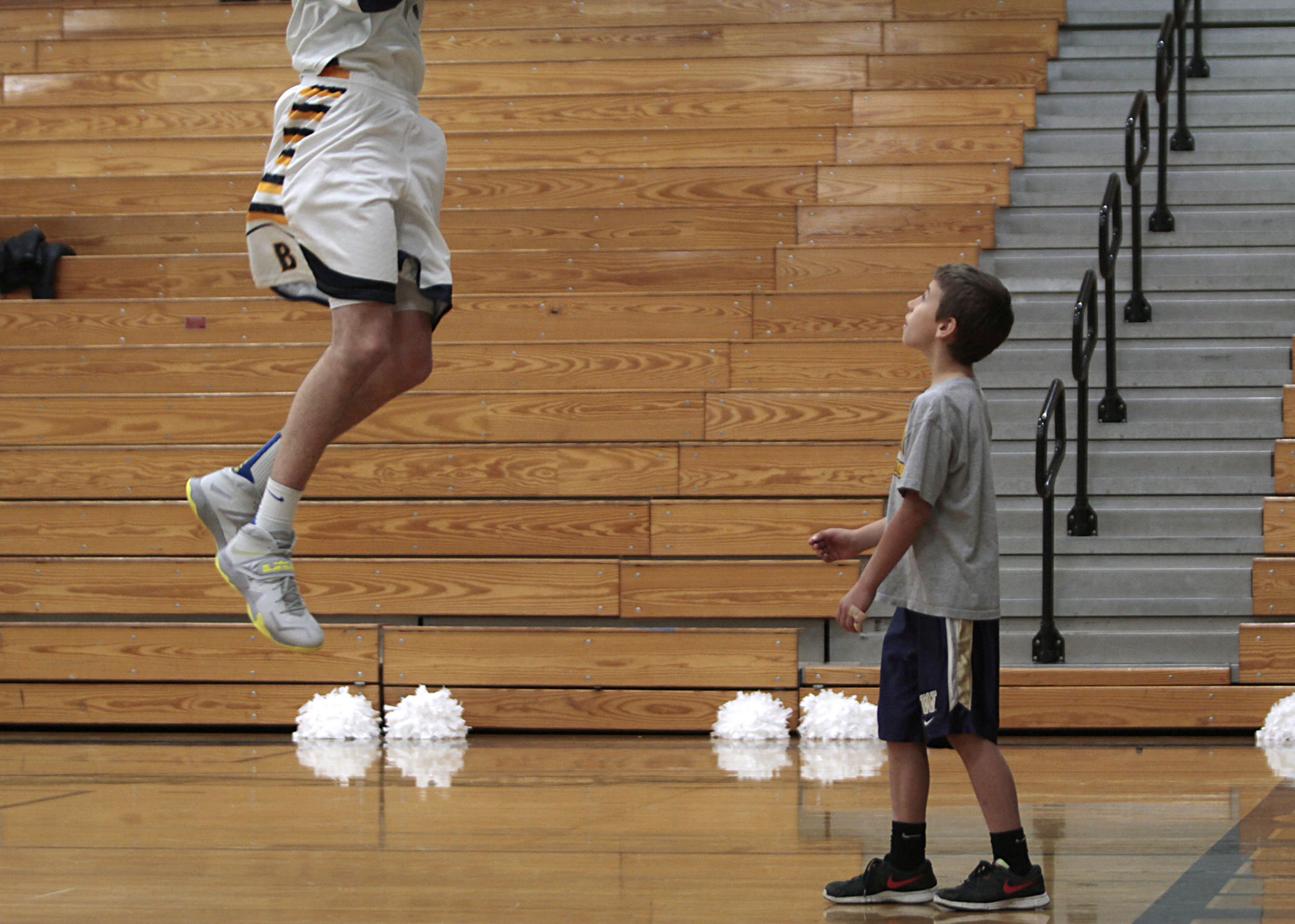  Cade Orness, 8, son of Bainbridge High boys basketball Head Coach Scott Orness, gets closer than the average fan as he watches from under the net as a player goes up for a rebound during a warm-up session.&nbsp; 