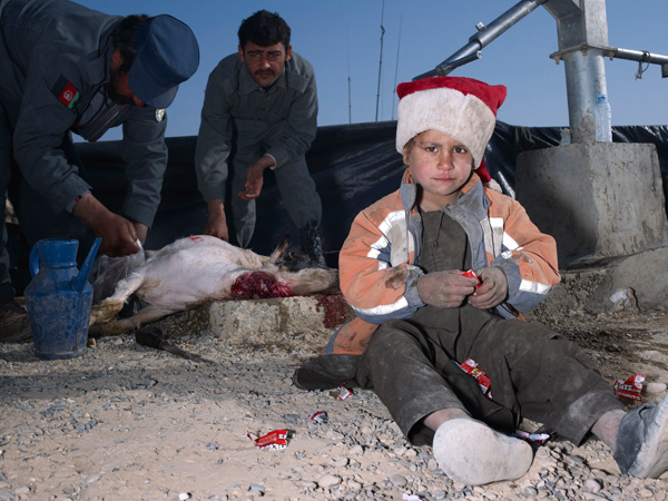 Child, Jacket, Slaughtered Goat, Sweets, Painted Nails, Xmas Day, Helmand’, Mark Neville, 2010, c-type print