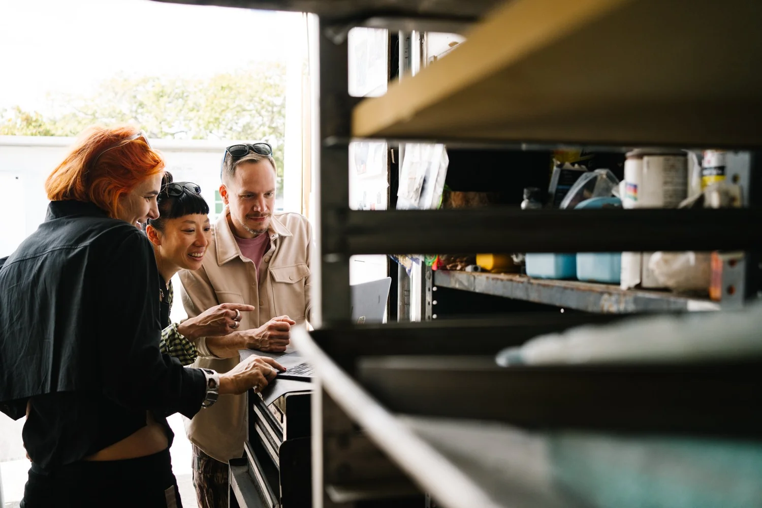 Archival photo from an earlier Baker’s Brunch at Bakehouse Art Complex: three visitors smiling as they look over work inside an artist studio