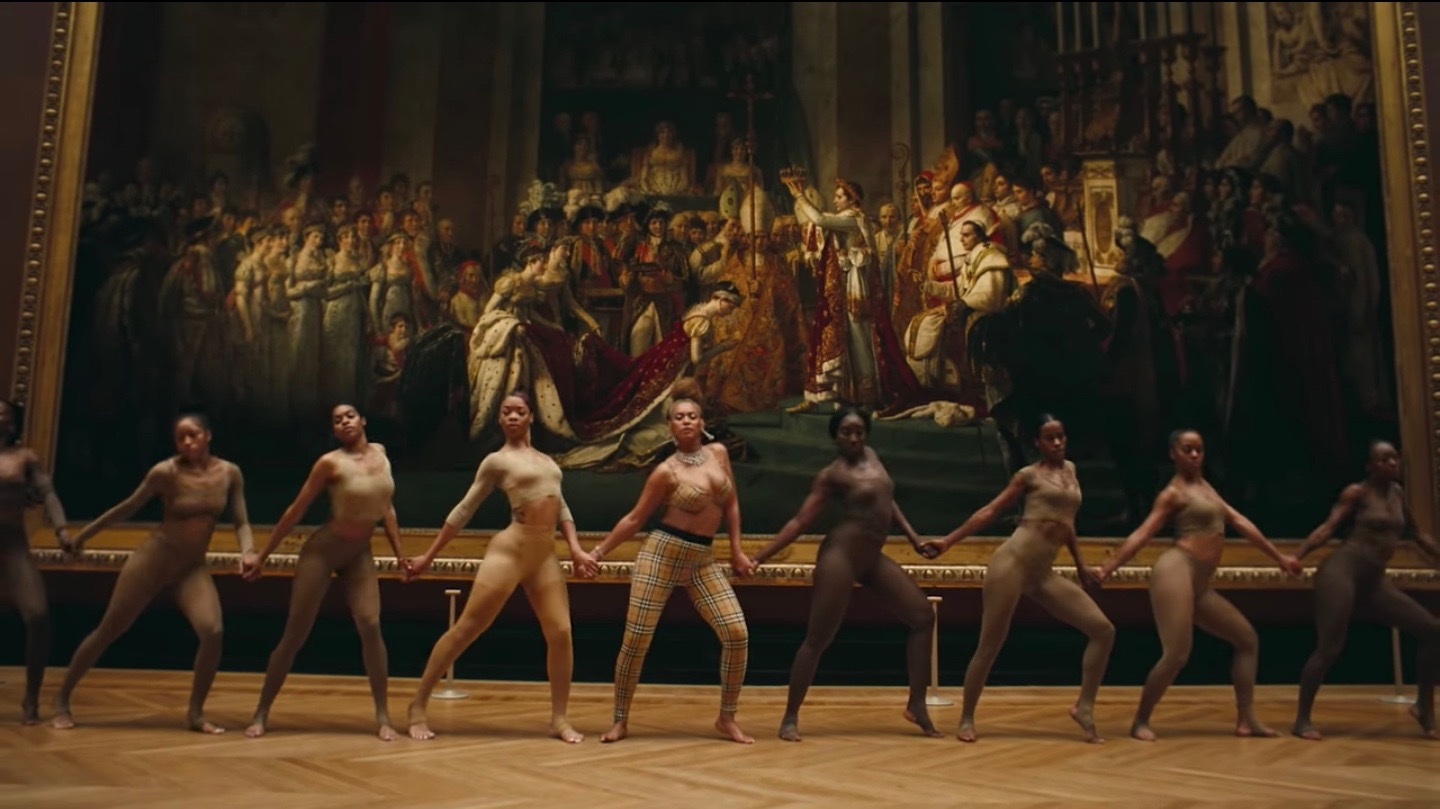 A still from "Apeshit," Beyoncé dances with women in front of The Coronation of Napoleon .