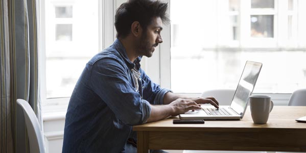 banking-blog-young-man-sitting-at-a-table-near-windows-looking-at-a-laptop.jpg