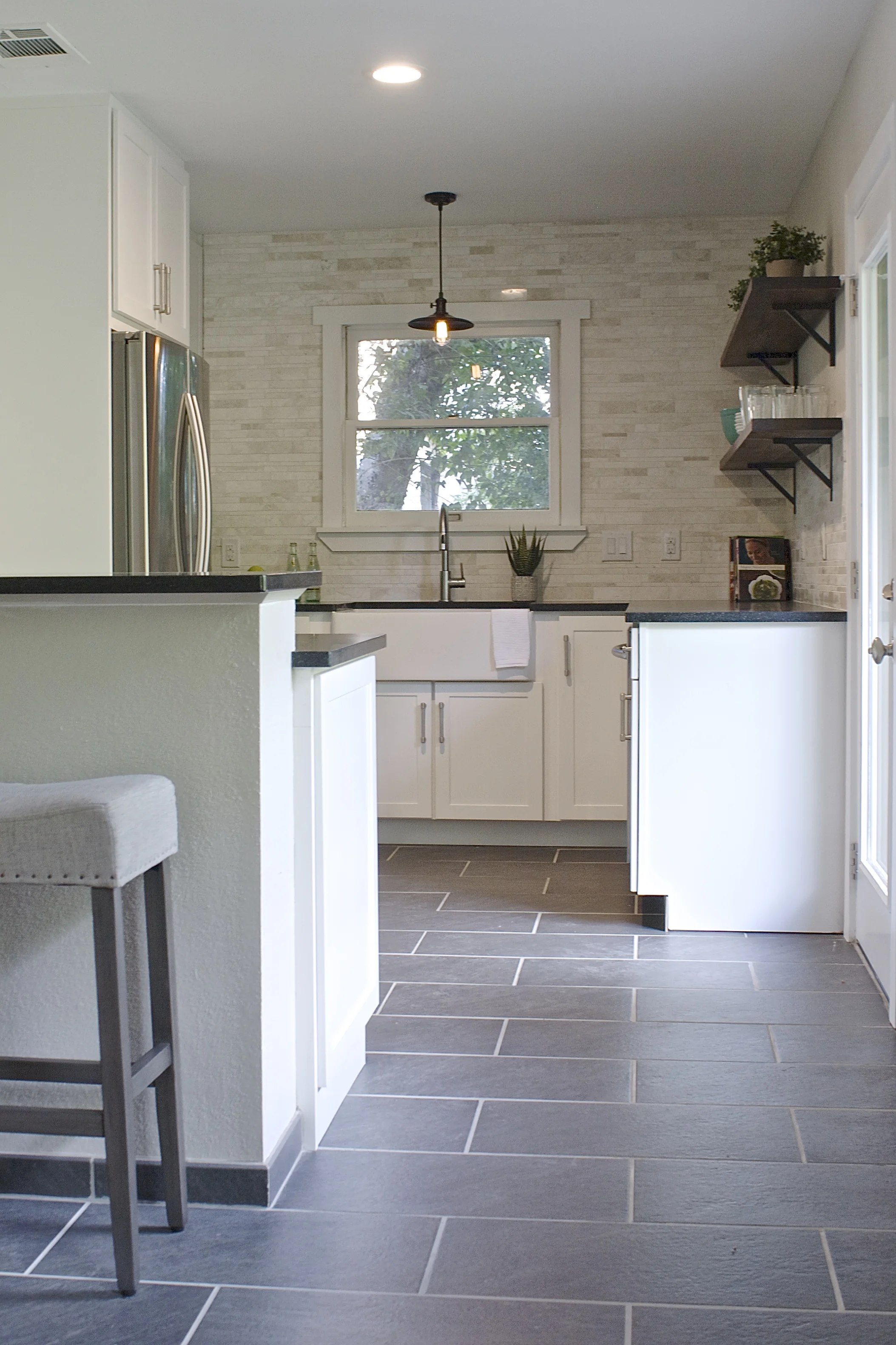 We removed the pantry and moved the water heater to the garage to open up the space. The range with a downdraft was moved to the peninsula to create more counter space. A 33" wide and counter depth refrigerator fits perfectly into the bright cabinetry!