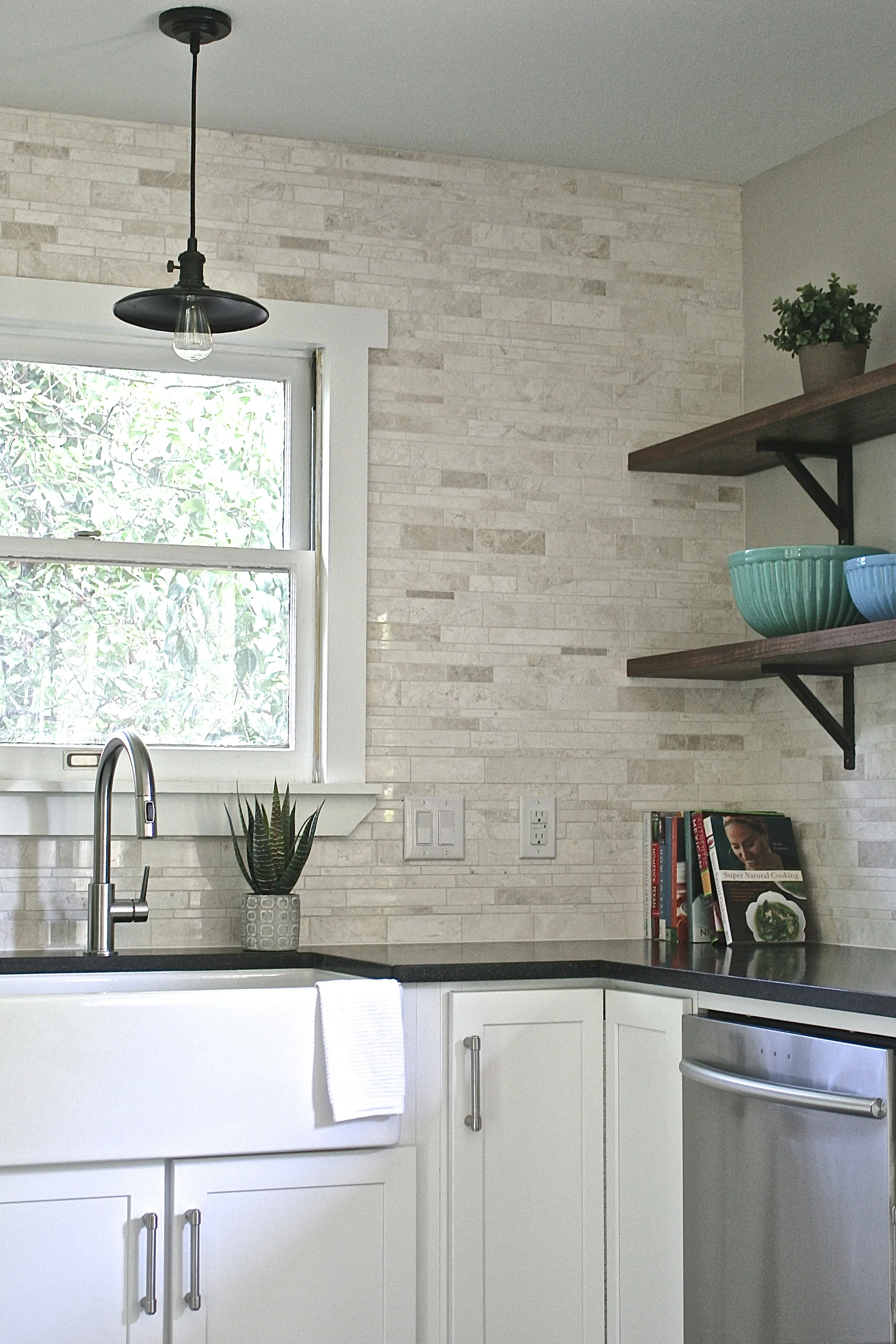 Removing the upper cabinets that flanked the window and adding the custom walnut shelving makes the kitchen appear larger and more open, while still providing lots of storage for dishes, etc. There's also a niche for a microwave oven at eye level in the cabinetry to the left that allows for even more counter space. The tile is a Terra Nuova brushed marble linear mosaic that feels organic, fresh and warm and was only $10/square foot. Countertops are honed black granite, which will be extremely durable and easy to maintain.