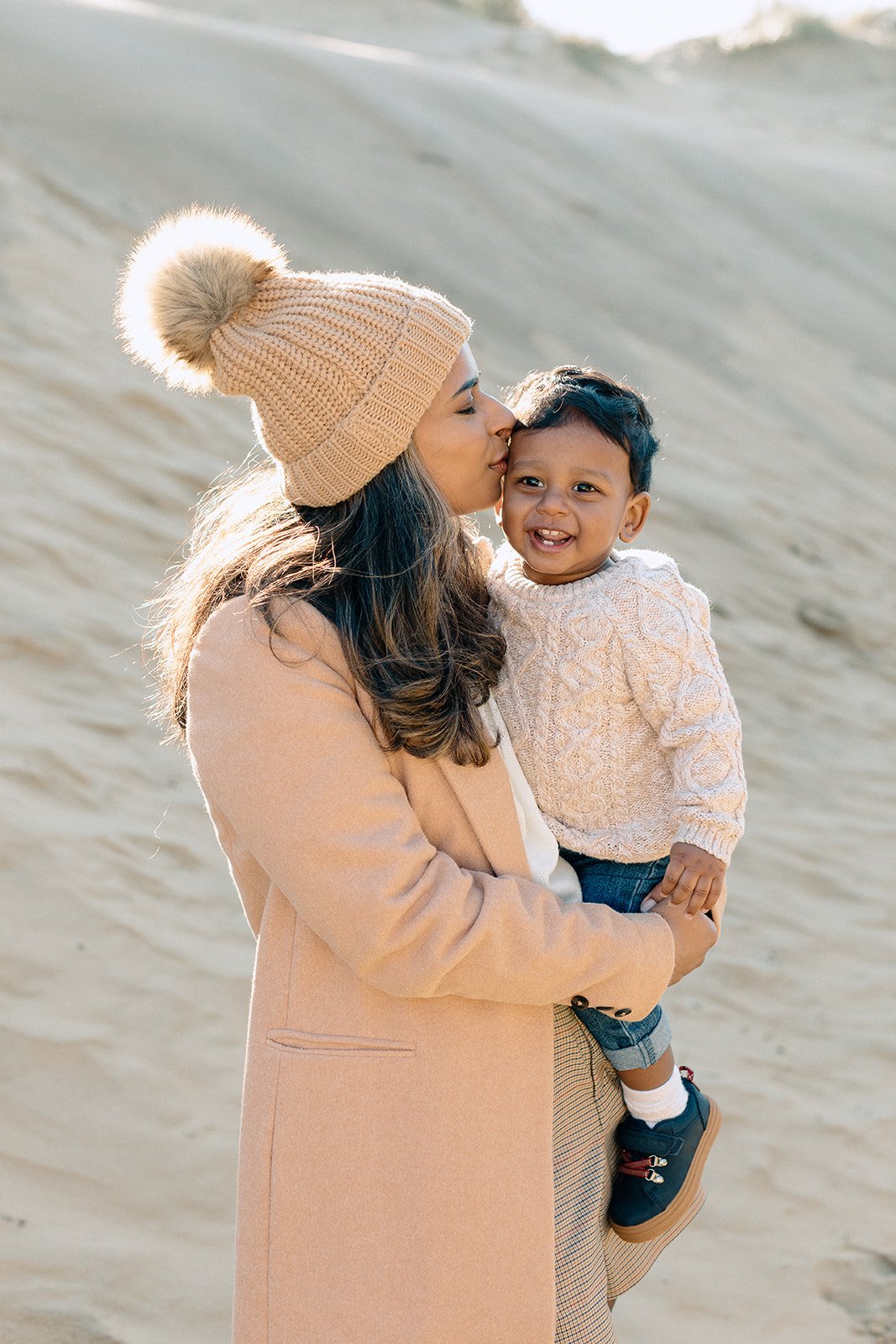  family photographer captures mother holding toddler at Camber Sands, Rye 