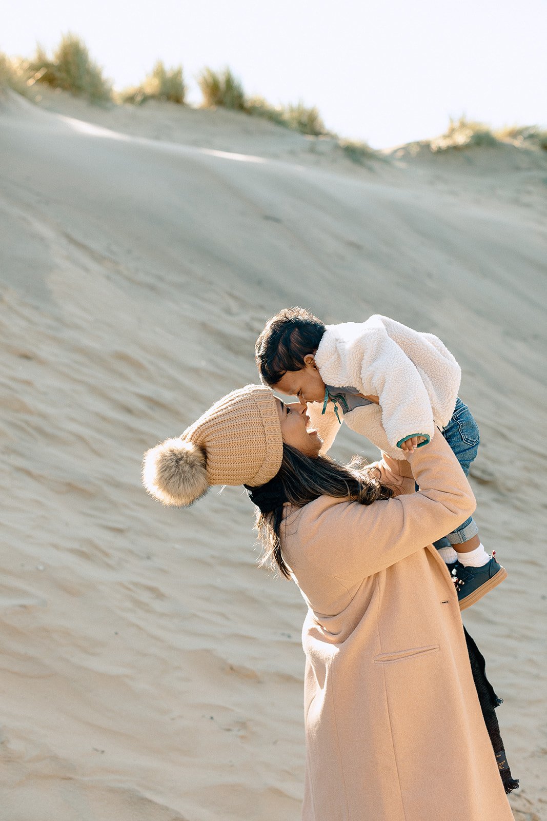  family photographer captures mother holding toddler at Camber Sands, Rye 