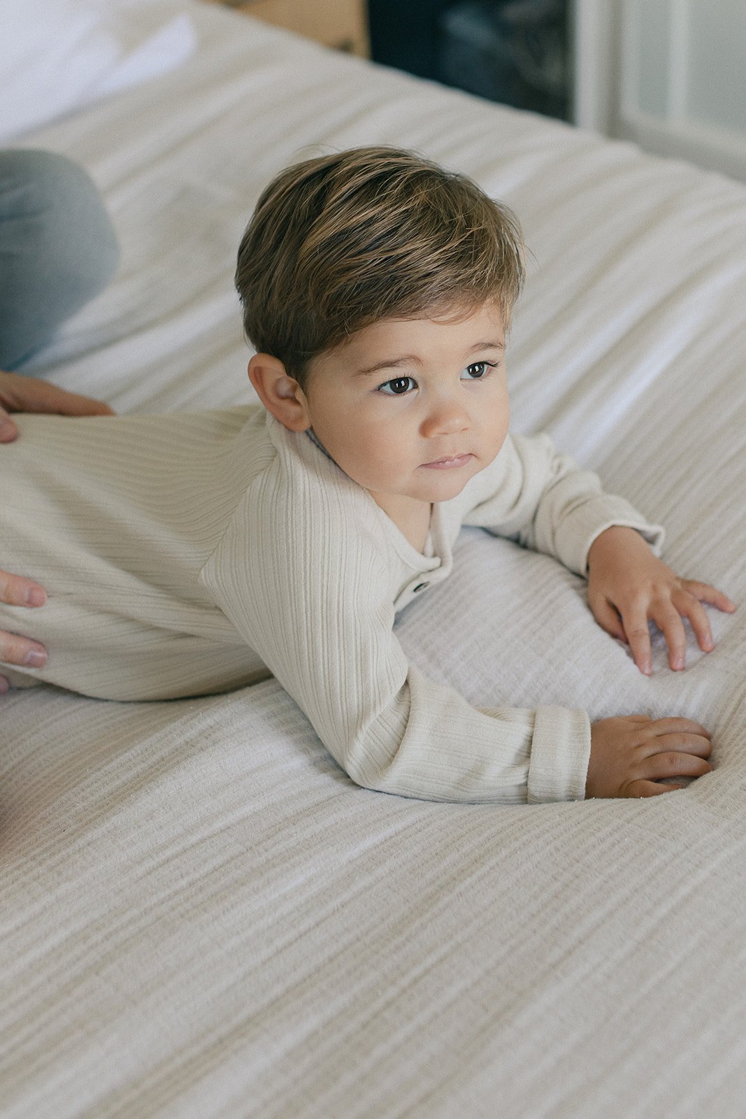  toddler lying on bed at newborn photoshoot 