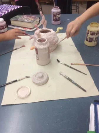 6th grade students work together to glaze their ceramic piece.