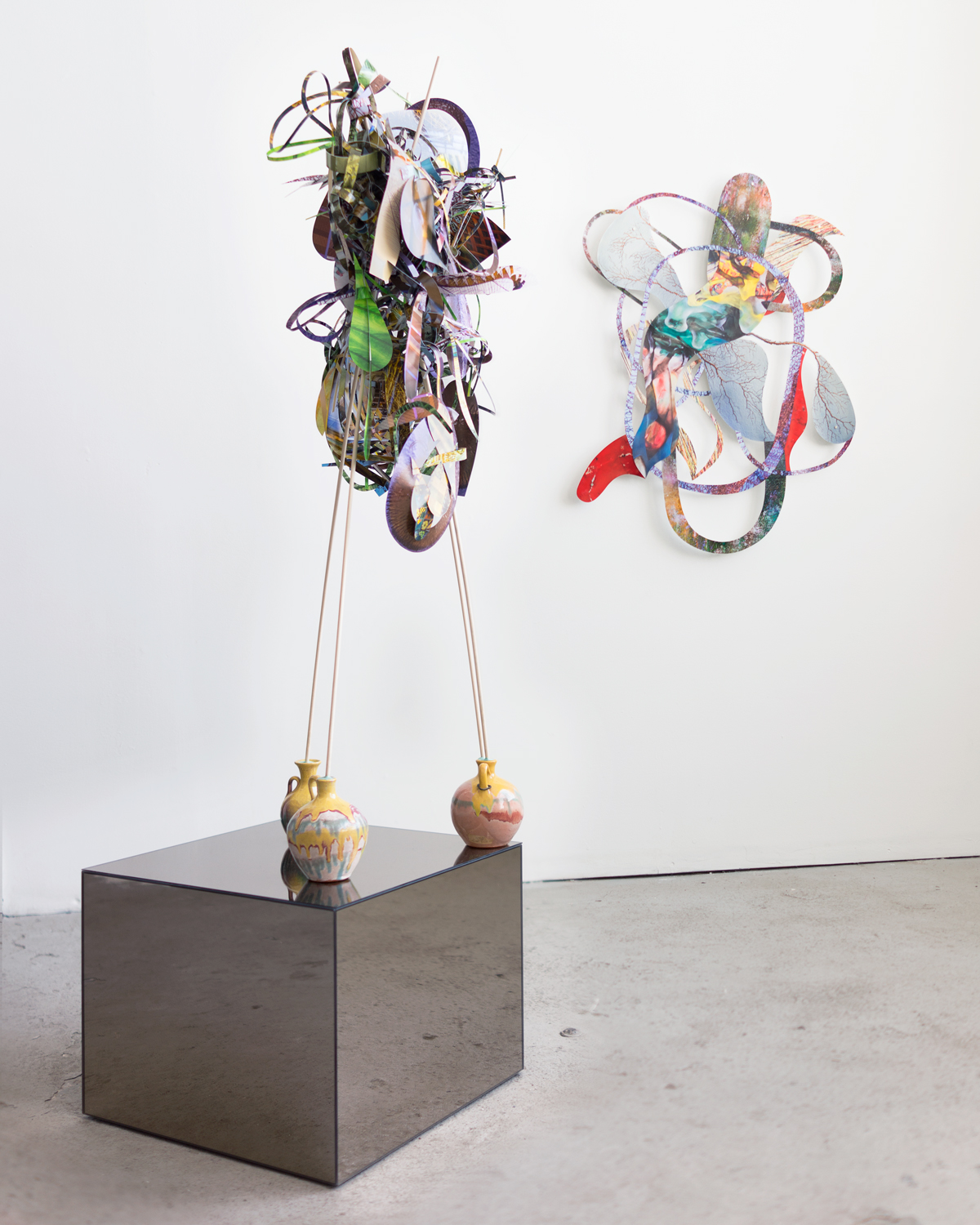   Zig-zag-tongues-tides , 2014  cut-up inkjet prints, wooden dowels, ceramic jugs, museum putty, and mirrored side table  63 x 18.5 x 18.5 inches    on the wall:   Around getting through , 2013  cut-up inkjet prints  39 x 29 inches   Twist-flip-tremb