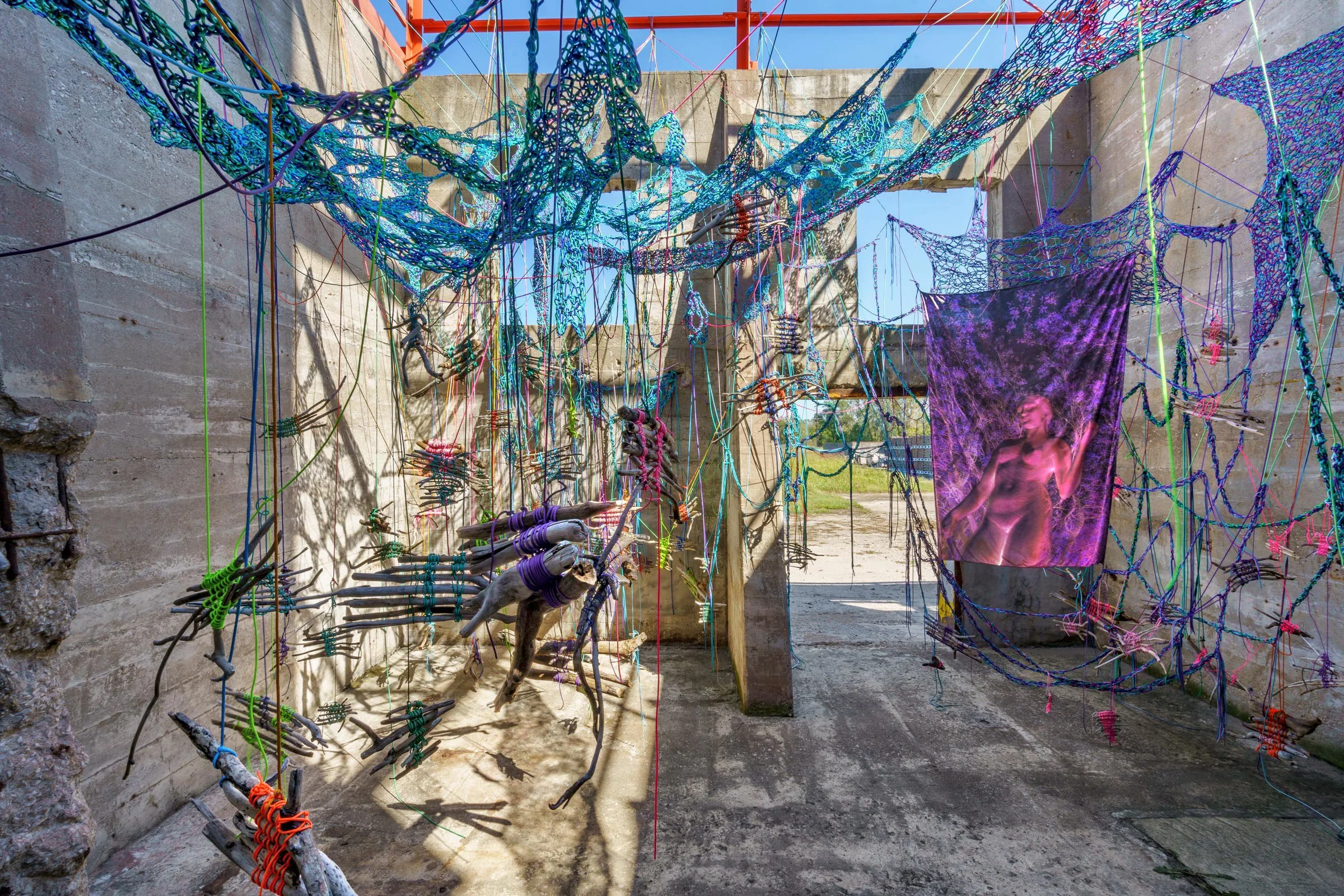  Hold Tight, 2024  Materials: Photographs, paracord, driftwood  Dimensions: Site-specific installation in 418 square foot unconventional, outdoor exhibition space with 15foot tall walls  Exhibition: Solo exhibition at NON STNDRD, Sauget, IL 