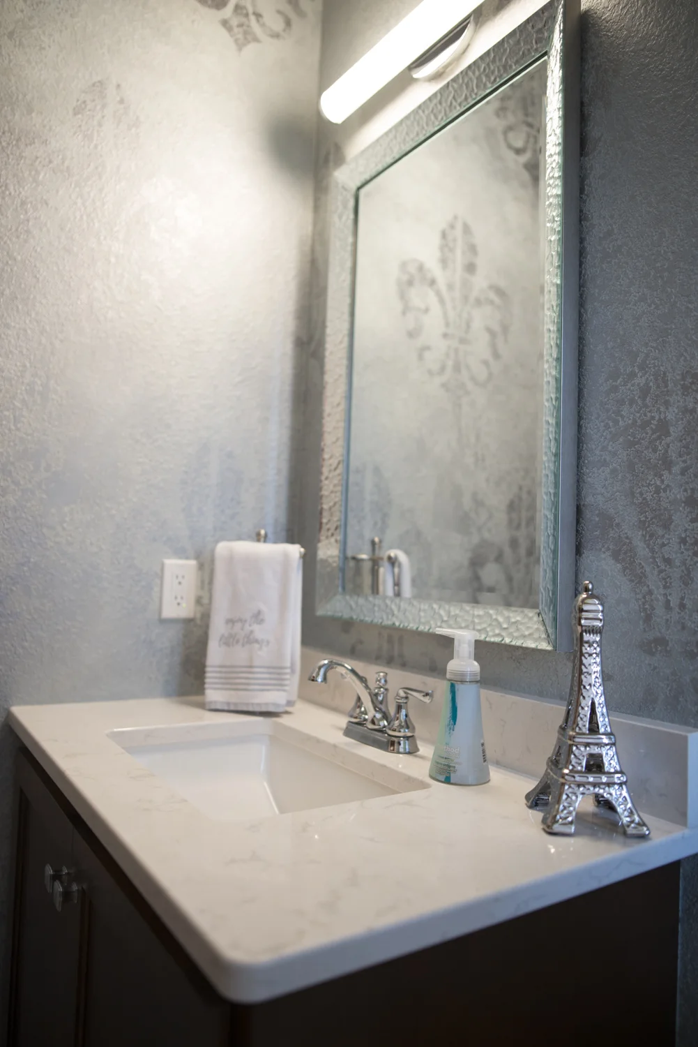 The half-bath walls were supposed to be smooth so they could be wallpapered, but due to a miscommunication with the builder it ended up with textured walls. No problem, Maranda hired local paint artist, Caren Brumleve, to paint this effect on the wall.