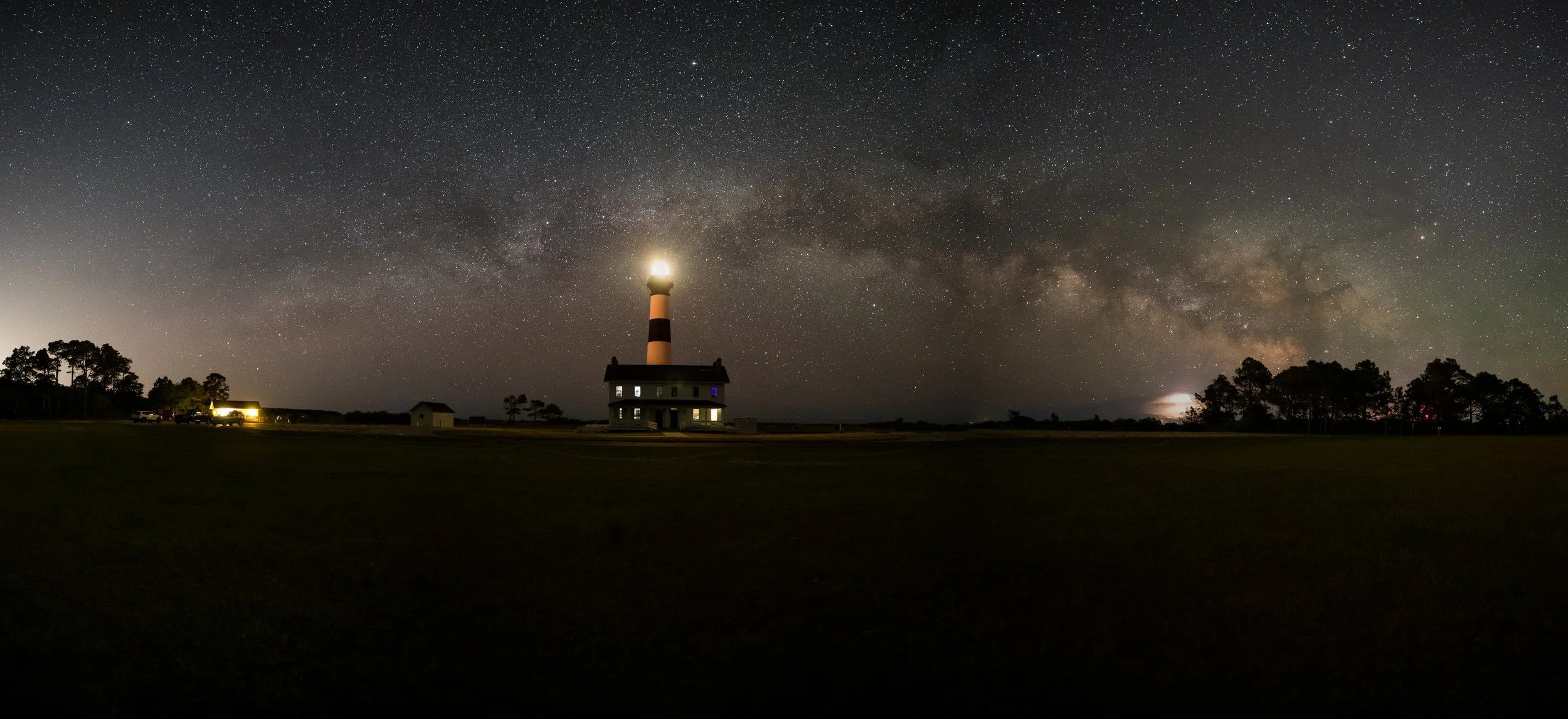 The Shape of Departure:
At the horizon, light takes many forms—celestial, electric, constructed—all converging in a single frame. The lighthouse stands steady, yet above it the Milky Way arcs into infinity while storms fracture the distance with